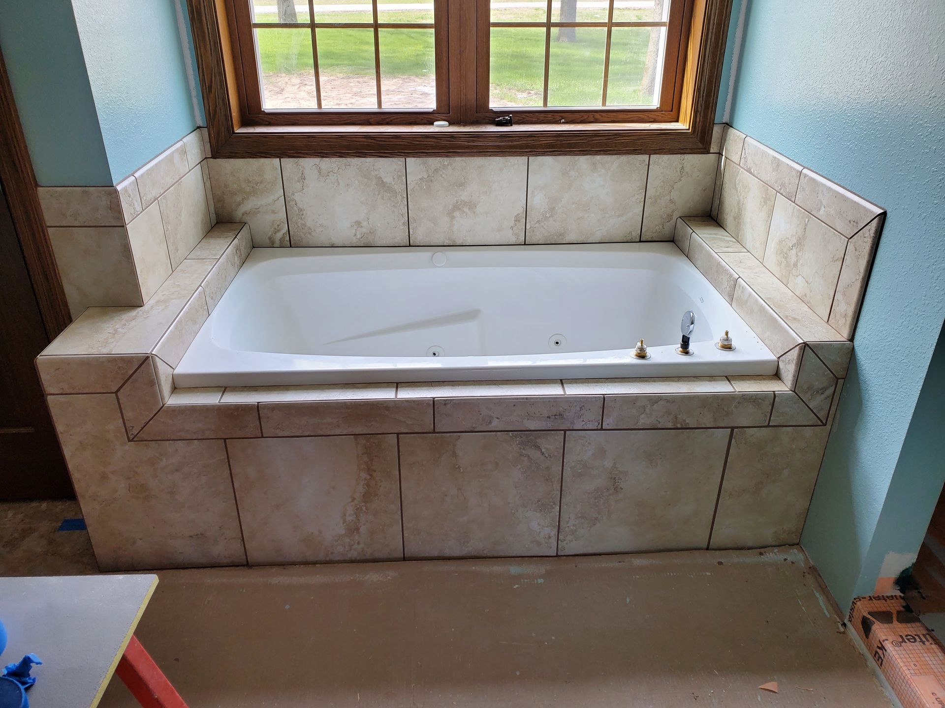 A bathtub is sitting in a bathroom next to a window.