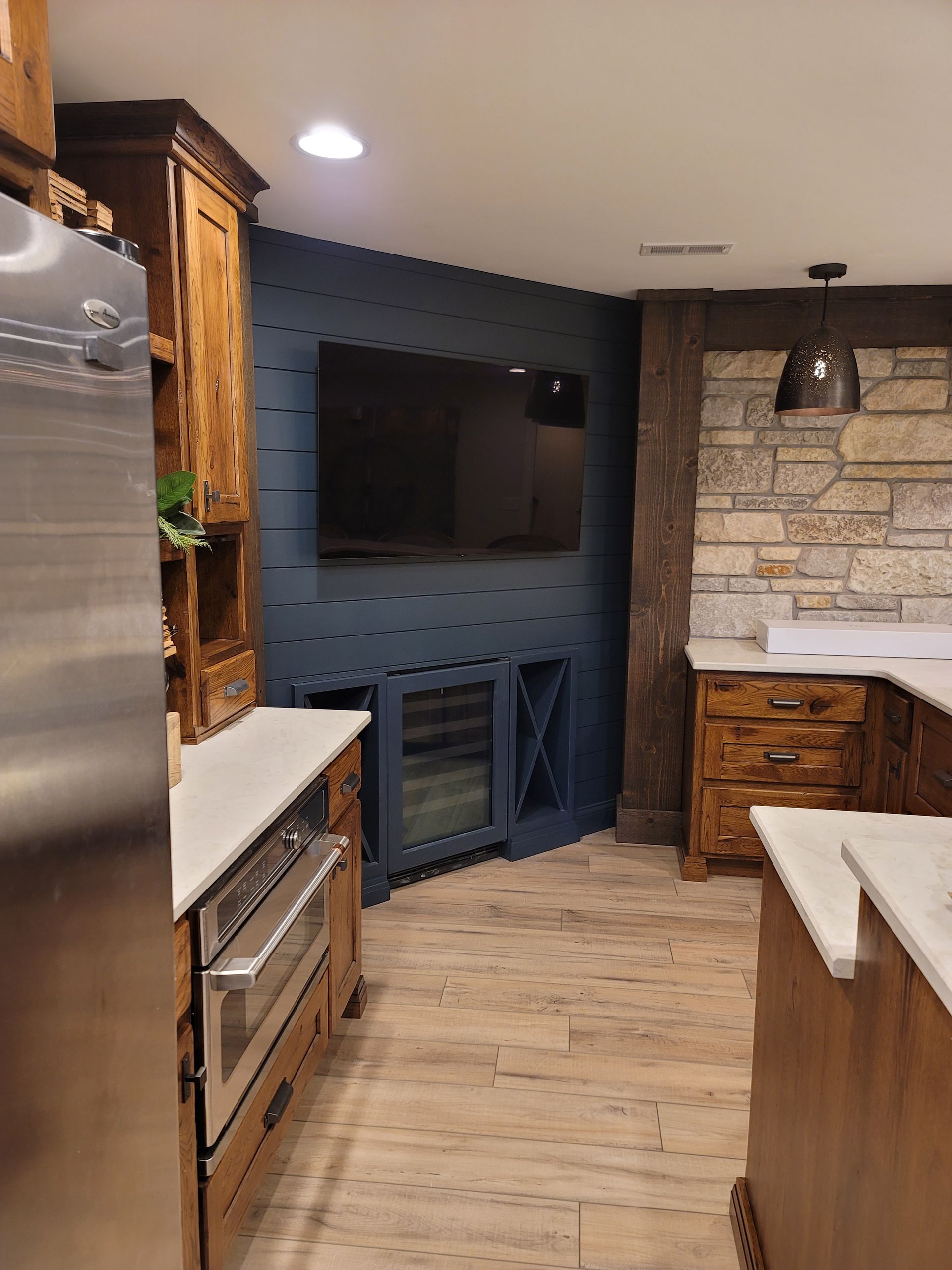 A kitchen with a large flat screen tv on the wall.