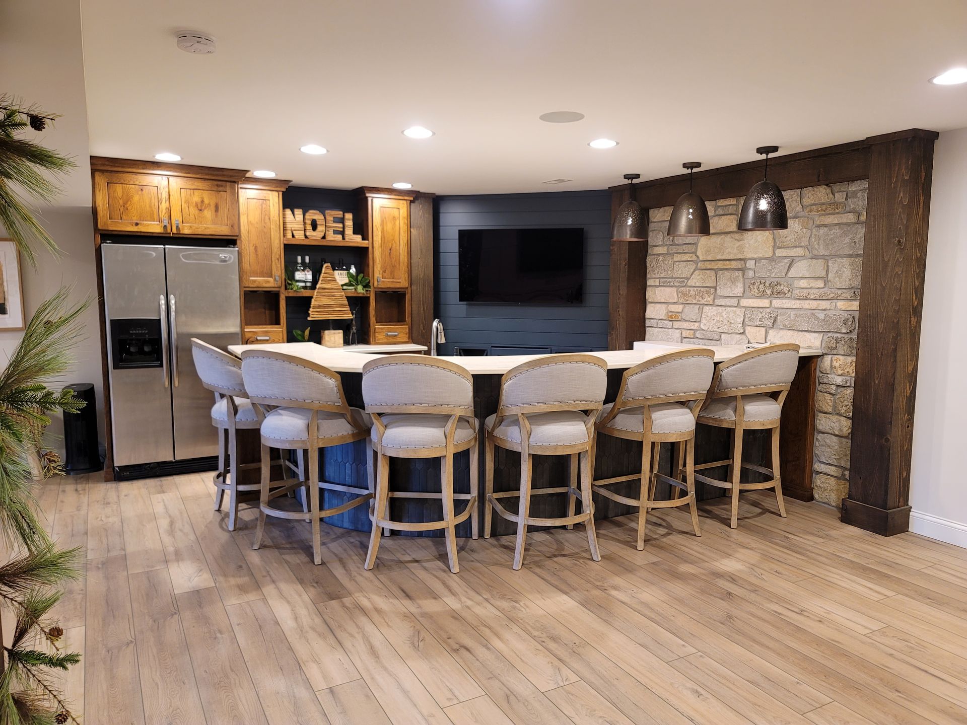A kitchen with a bar and stools and a refrigerator.