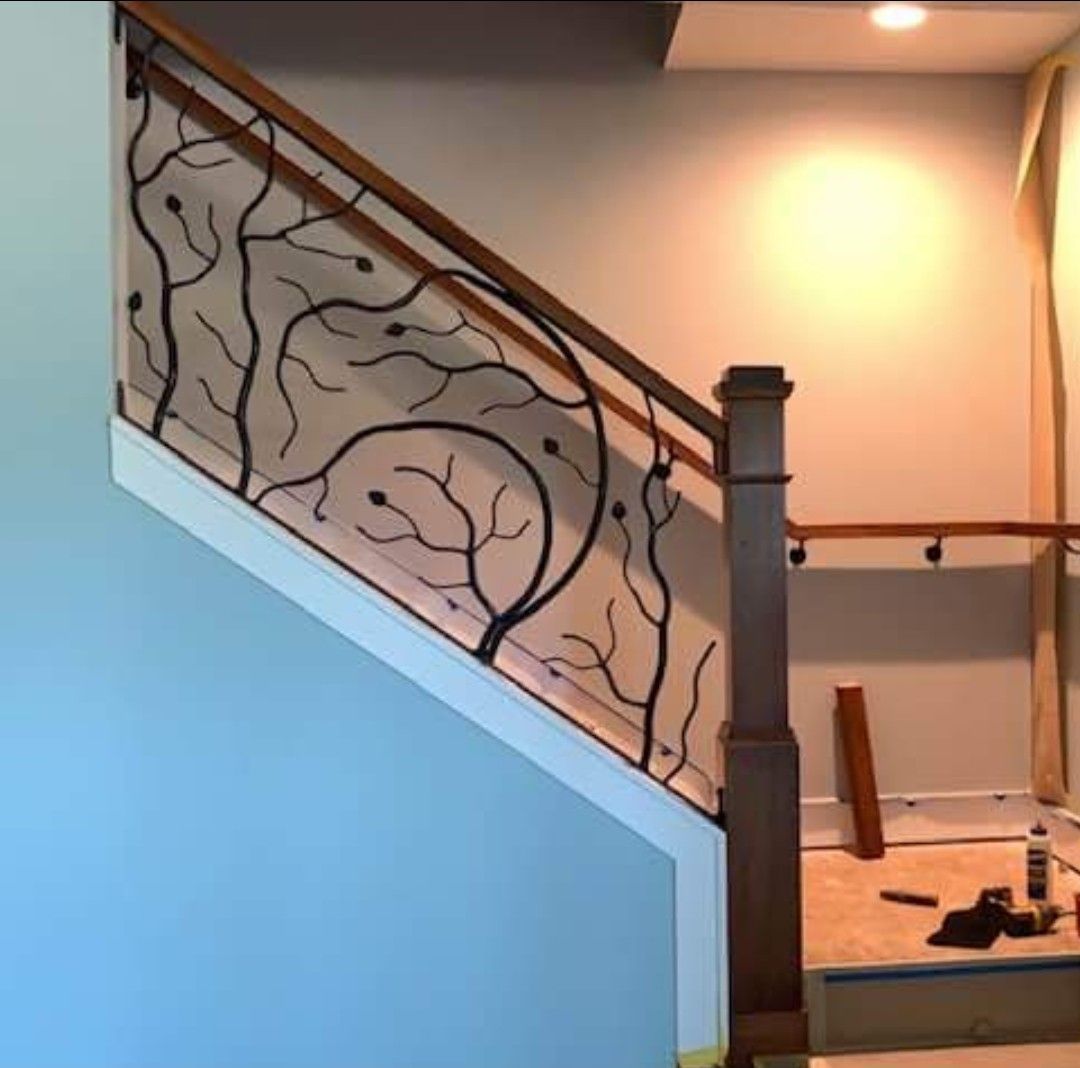 A staircase with a wrought iron railing and a wooden handrail