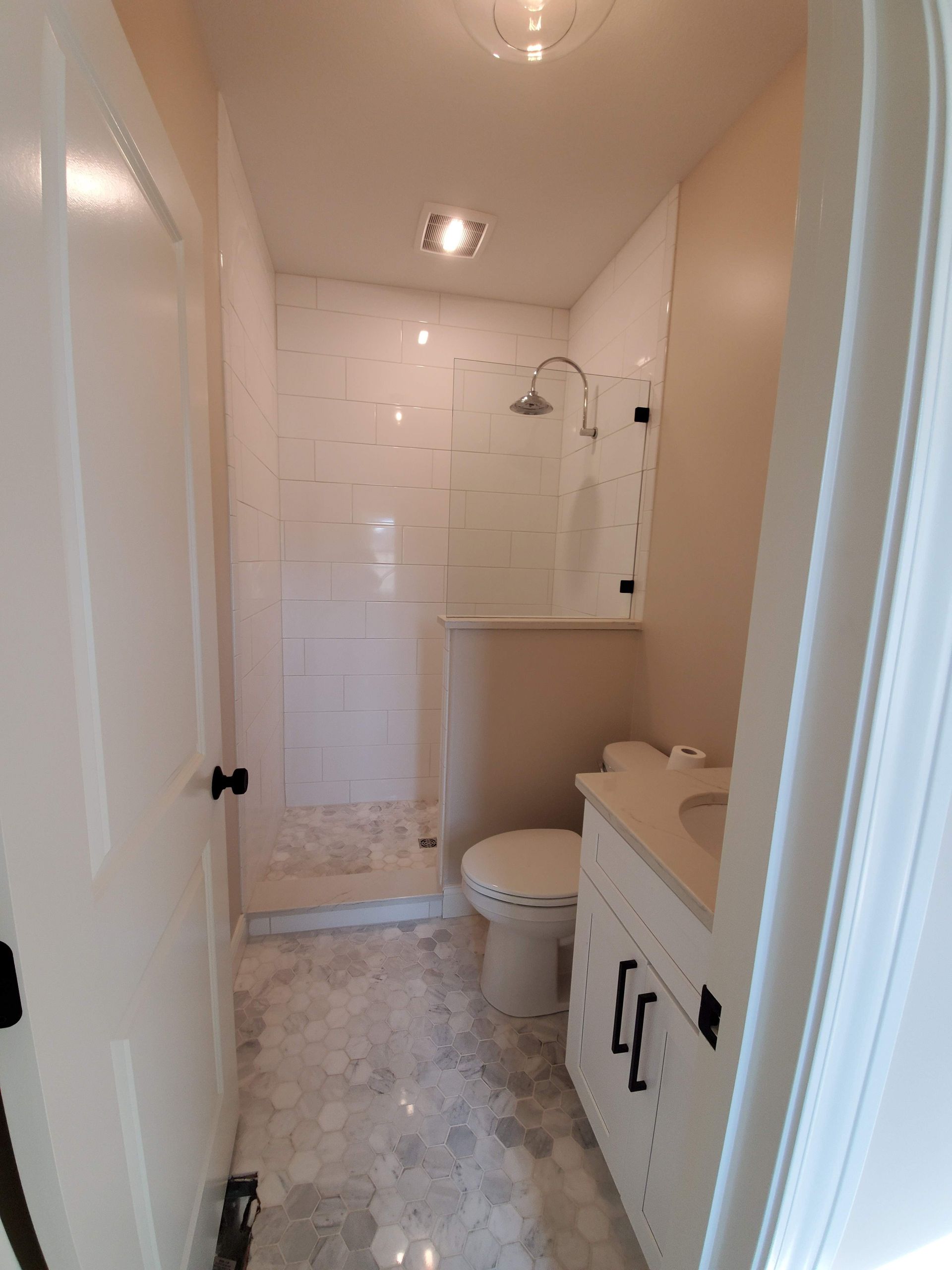A bathroom with a toilet , sink and shower.