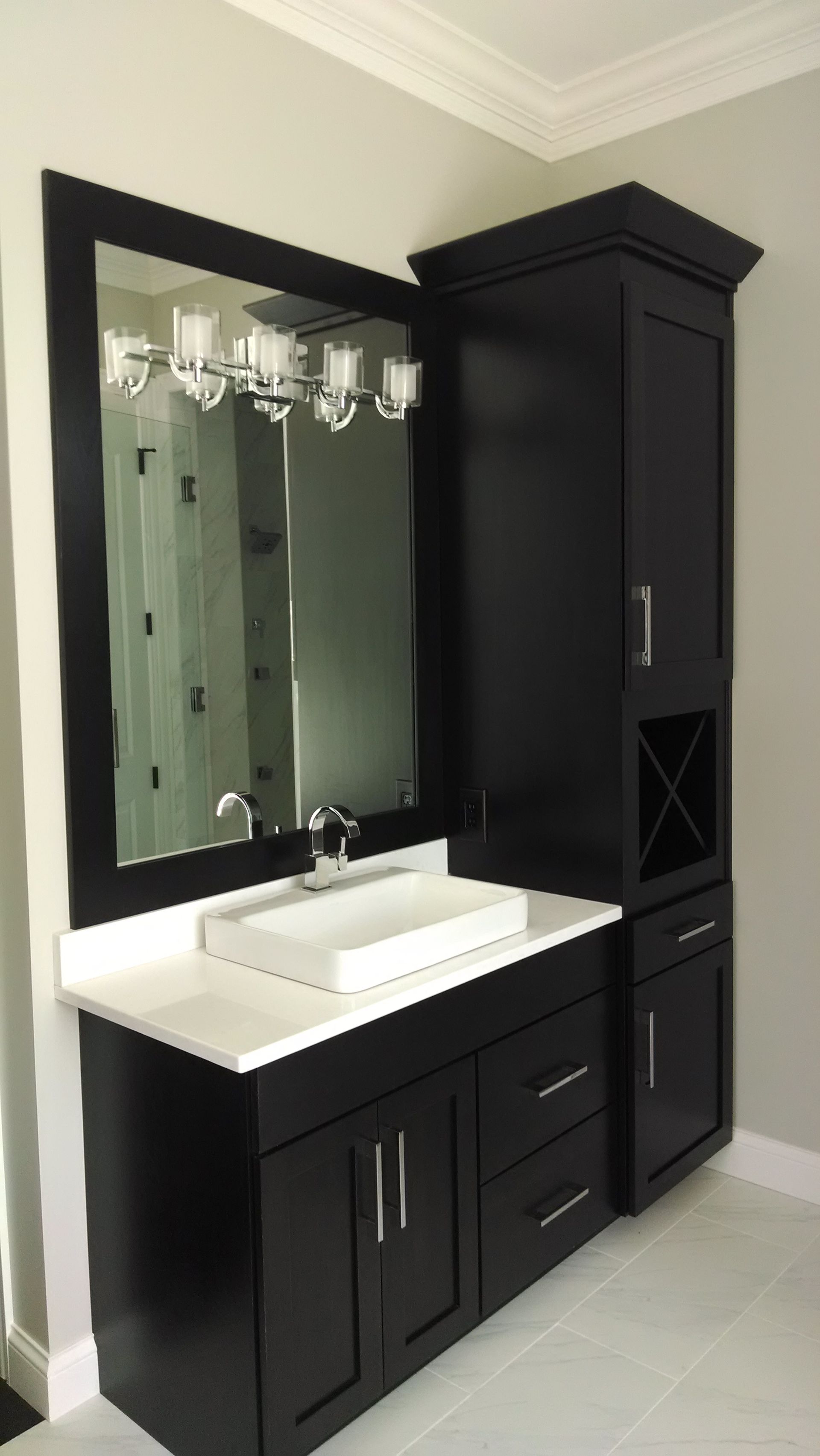 A bathroom with black cabinets a sink and a mirror