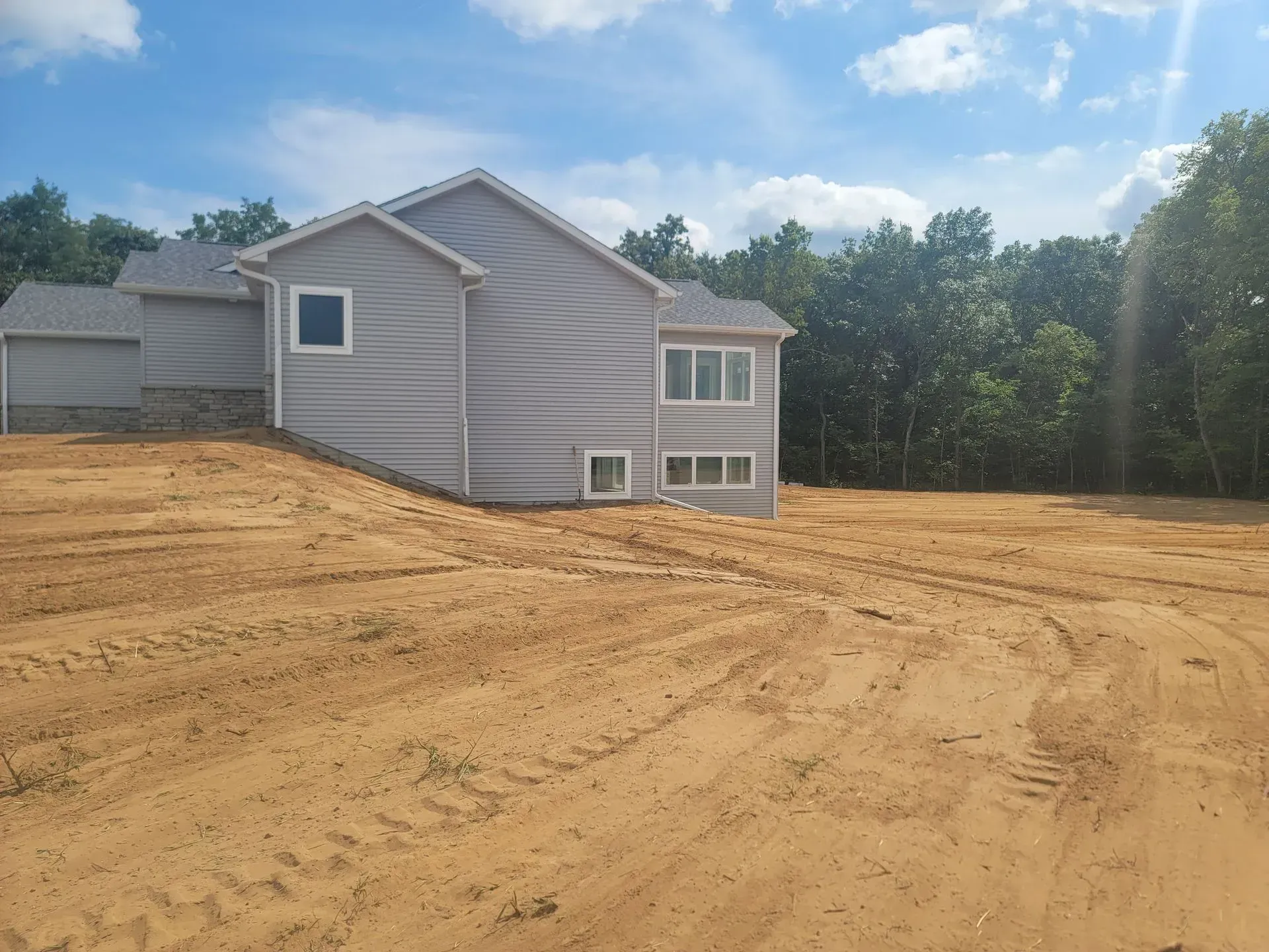 A house is sitting on top of a dirt hill in the middle of a dirt field.