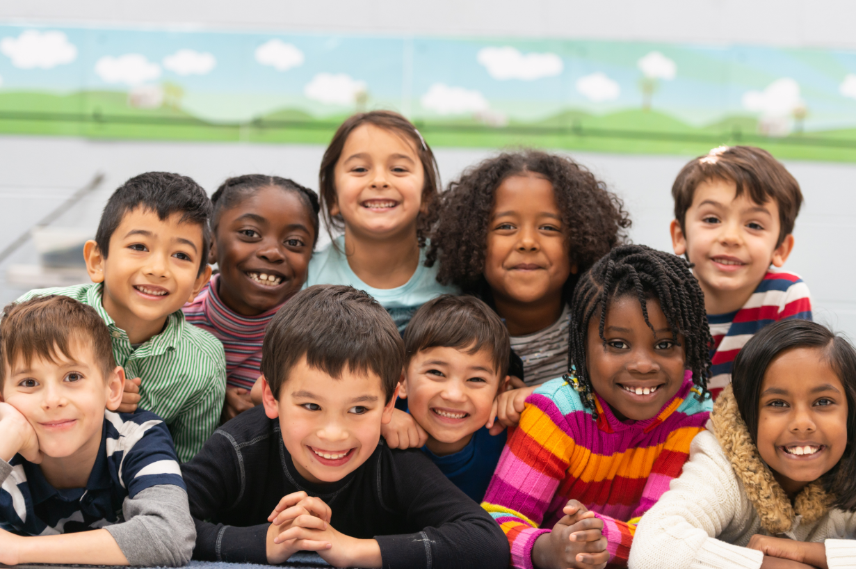 Smiling diverse group of children posing together indoors.
