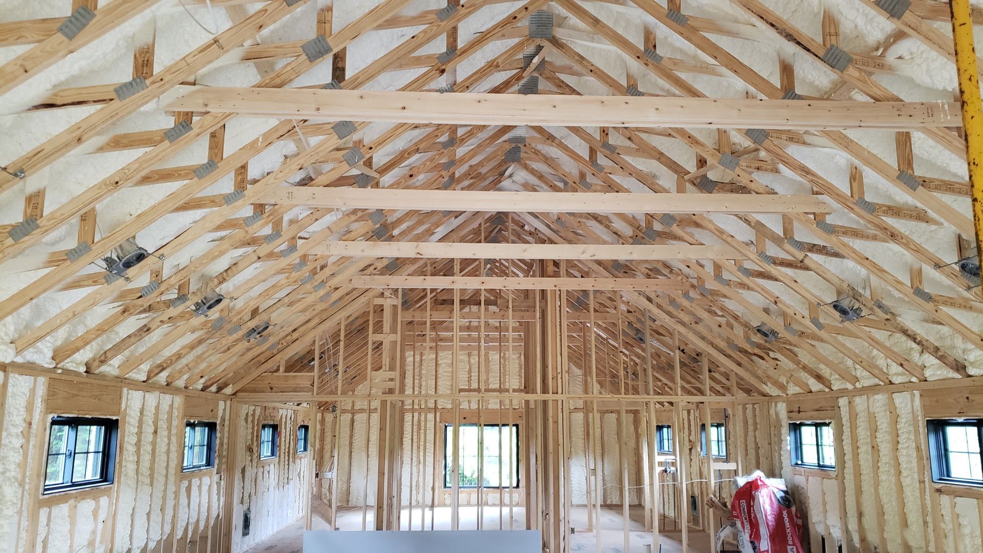 The inside of a house under construction with wooden beams and insulation.