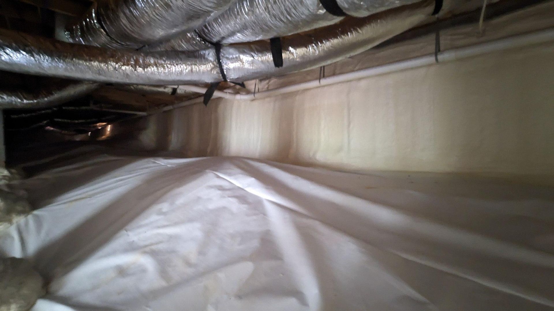 A room with a lot of pipes and a white sheet on the floor.
