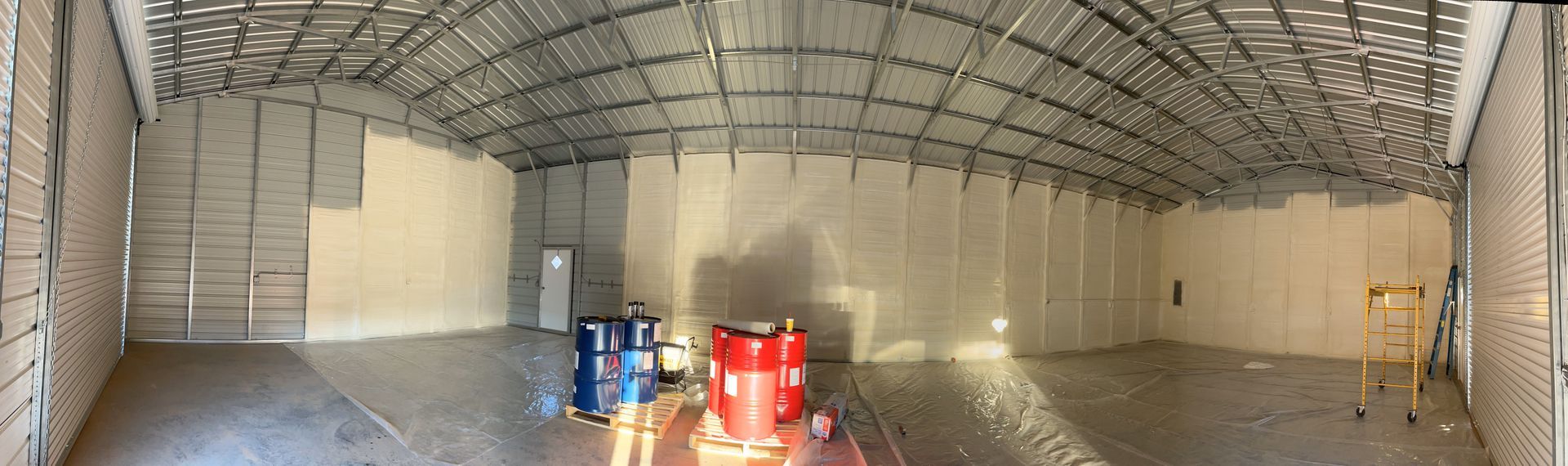 A large empty warehouse with a metal roof and a lot of windows.