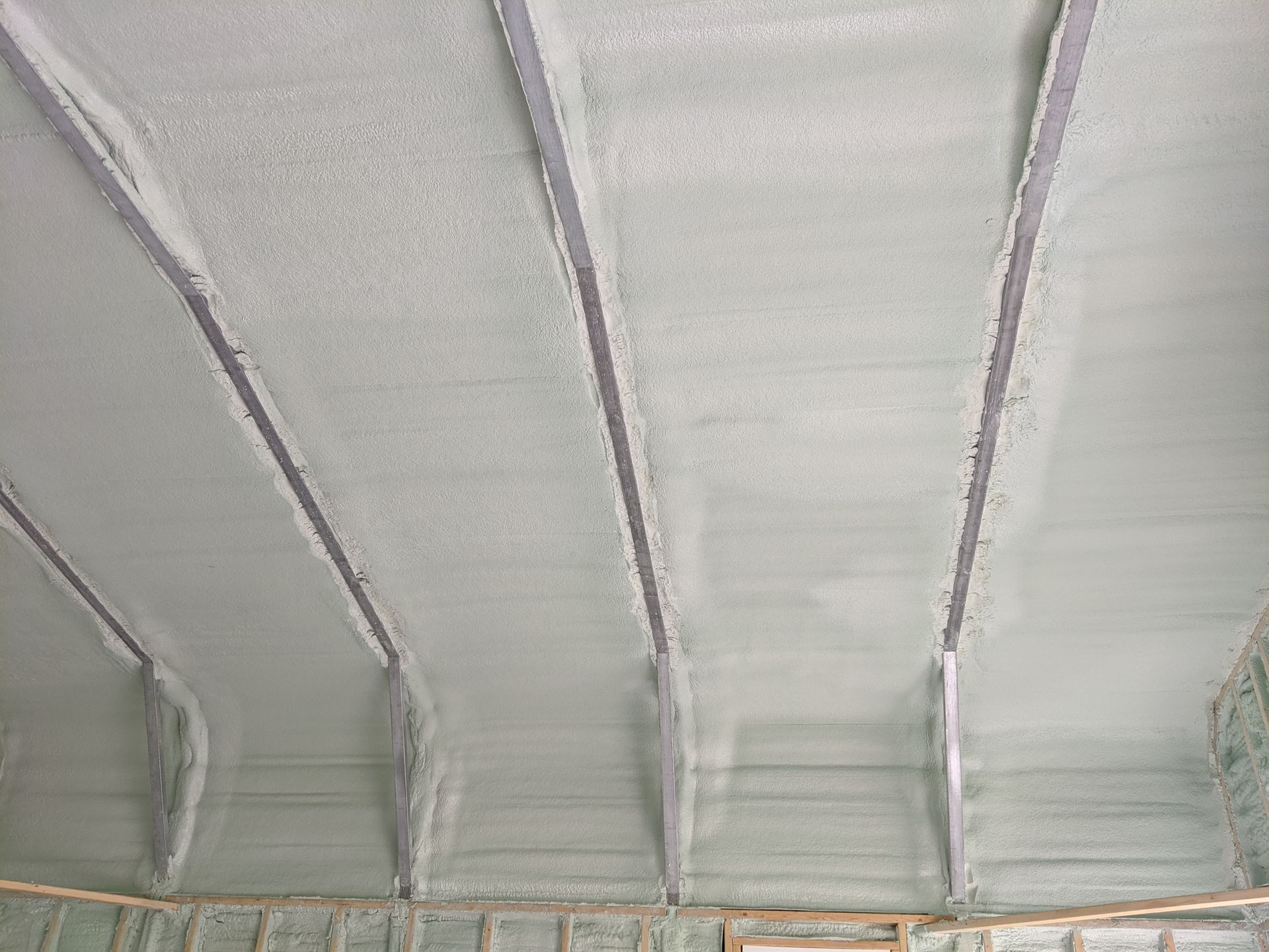 The ceiling of a building is covered in white spray foam.