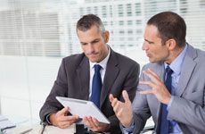 Serious businessmen analyzing documents on their tablet