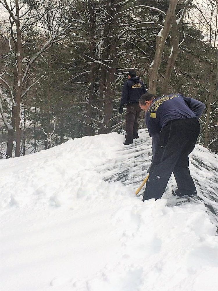 Two people shoveling snow on a snowy path in a wooded area