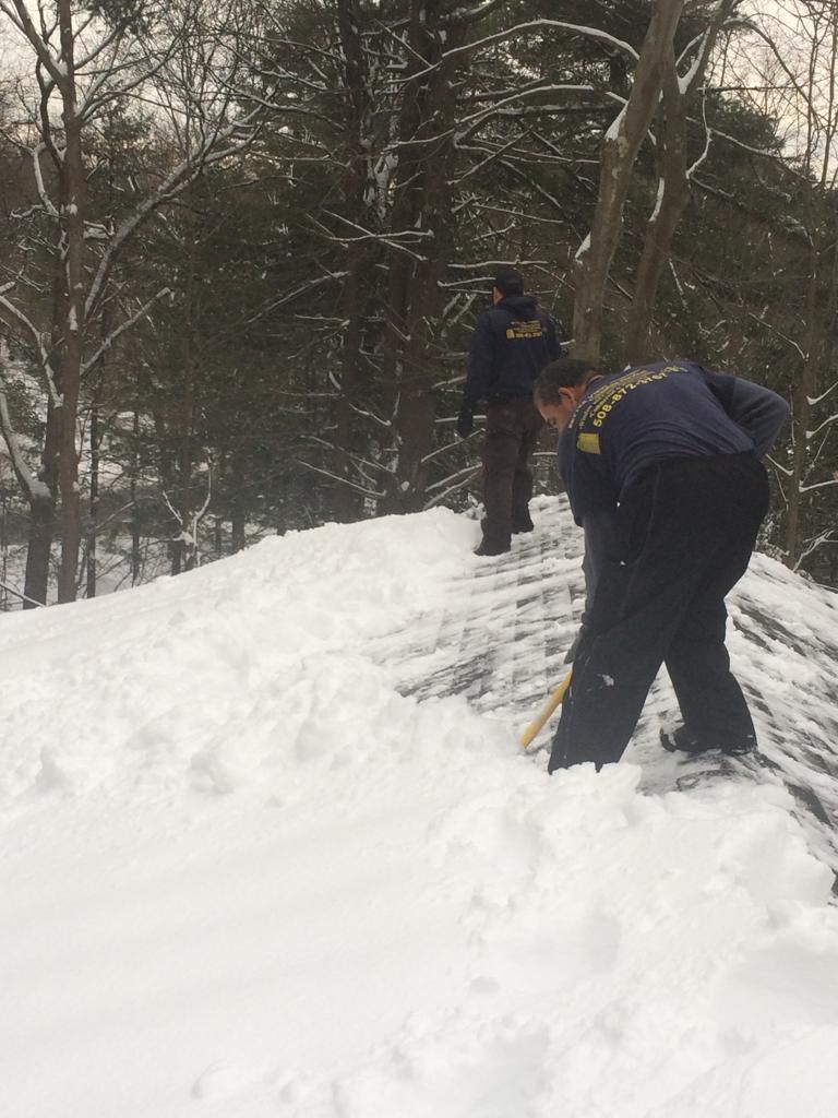 Two people shoveling snow on a wooded path in winter