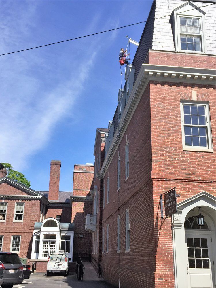 Worker on a rooftop beside a red brick building under a blue sky