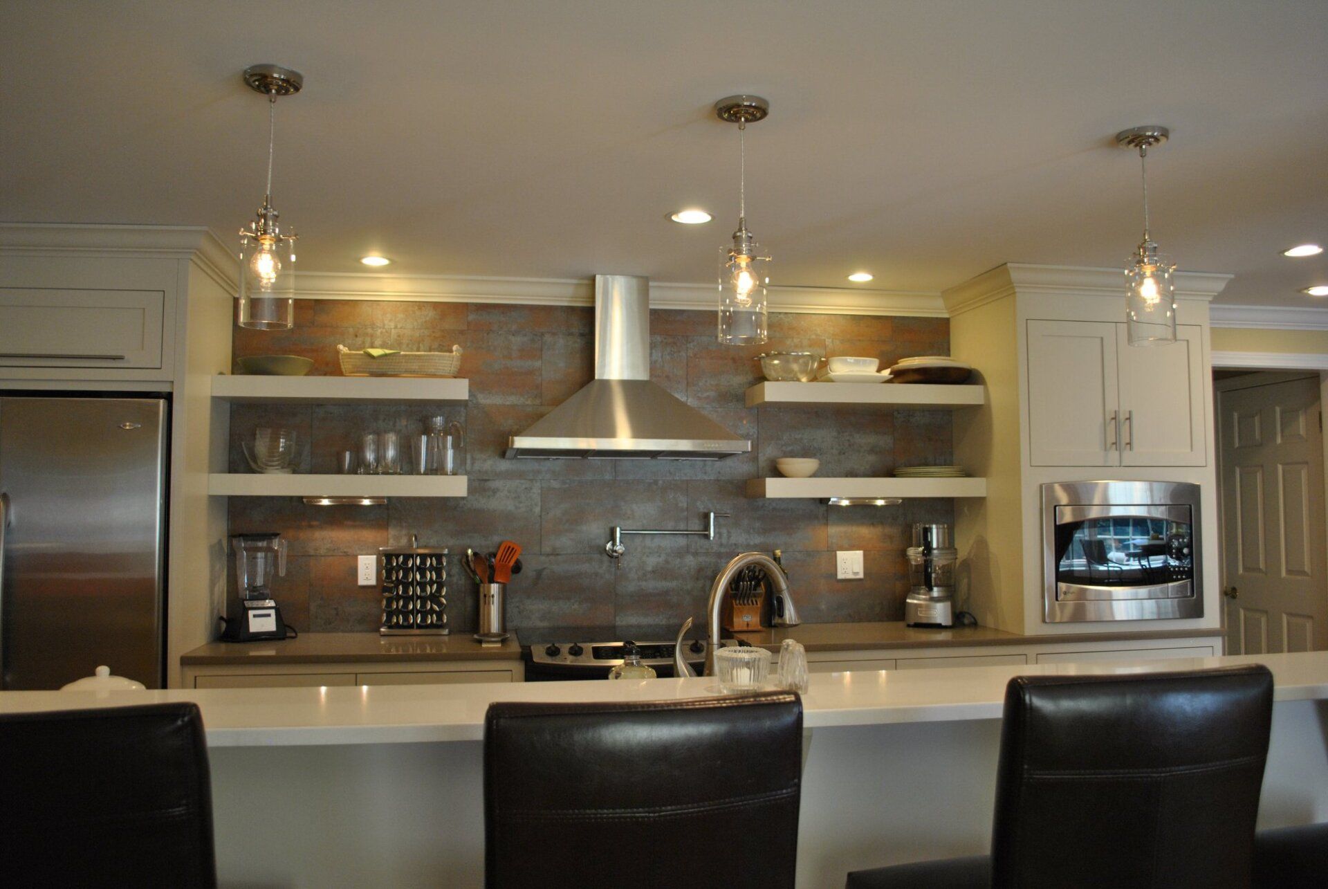 Modern kitchen with white cabinets, stainless steel appliances, open shelving, and a center island with seating.
