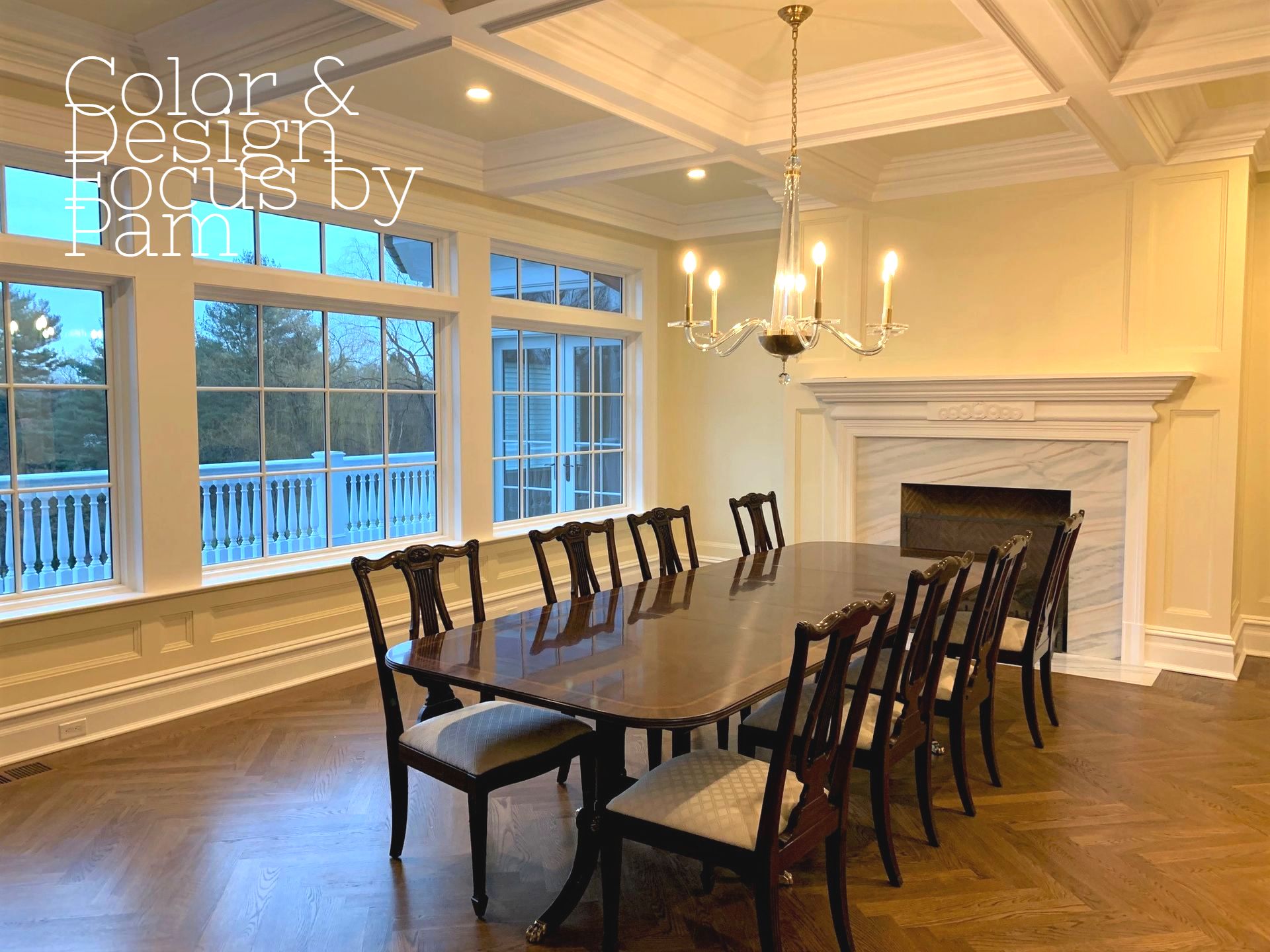 Elegant dining room with a long table set for a large gathering. Features include a chandelier, fireplace, and large windows.