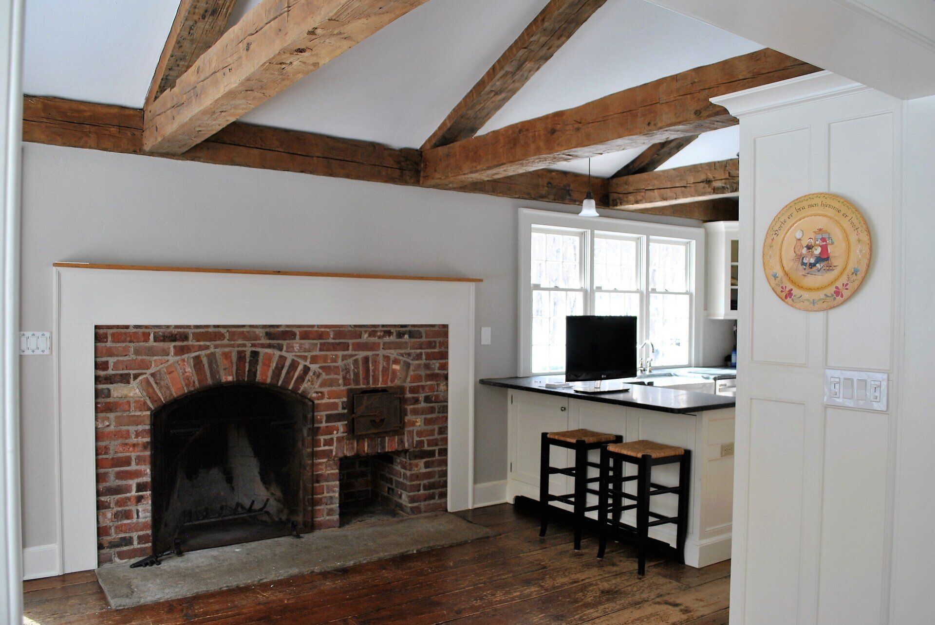 A living room with a brick fireplace and wooden beams