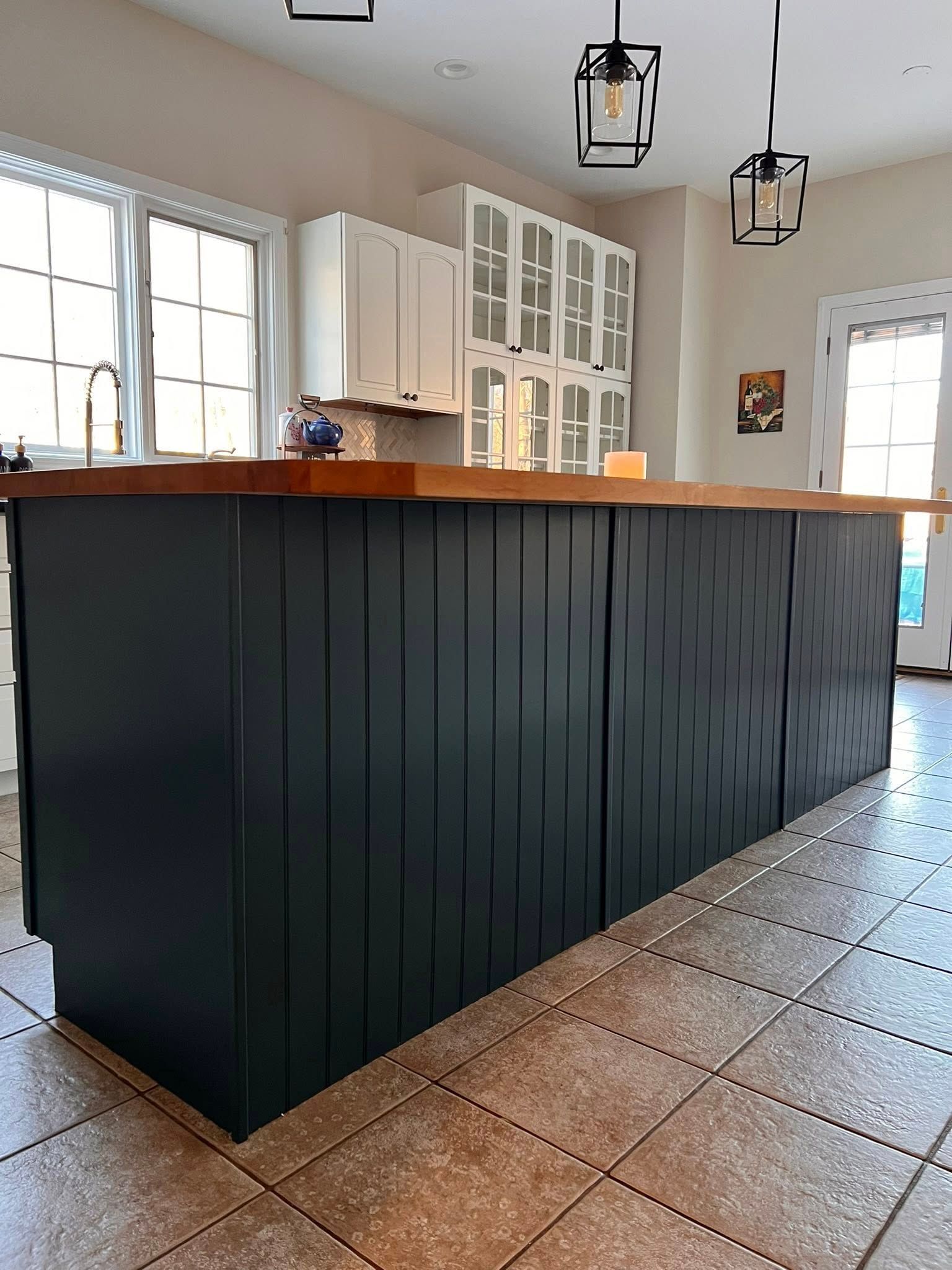 A kitchen island with a dark blue vertical-slat base and a natural wood countertop, situated in a home kitchen.