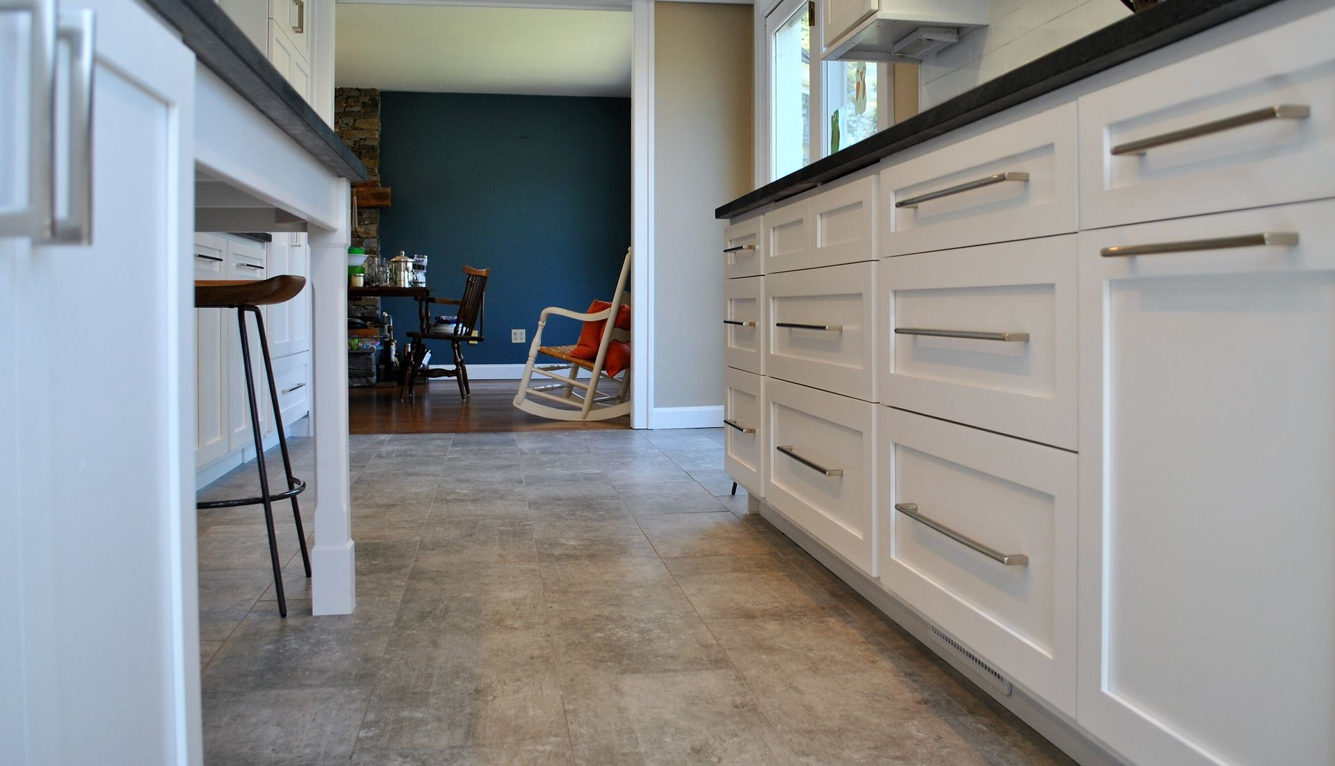 A kitchen with white cabinets and a rocking chair in the background