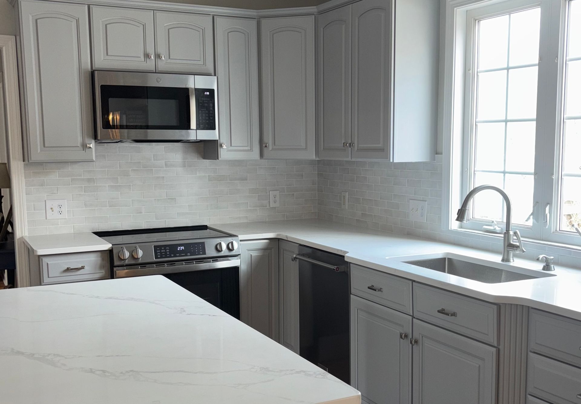 A kitchen with white cabinets and countertop
