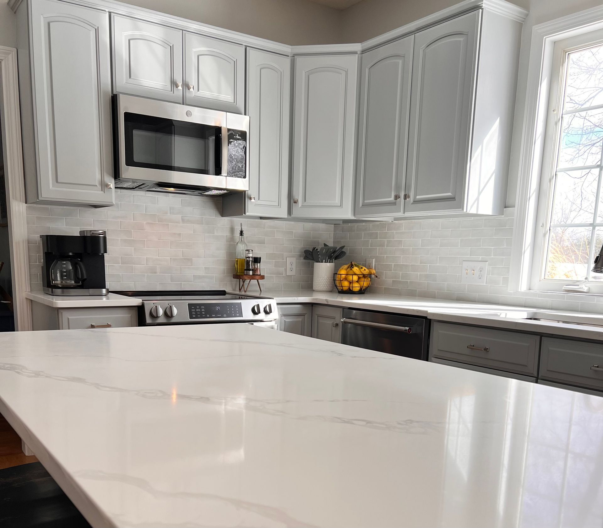 A kitchen with white cabinets and countertop
