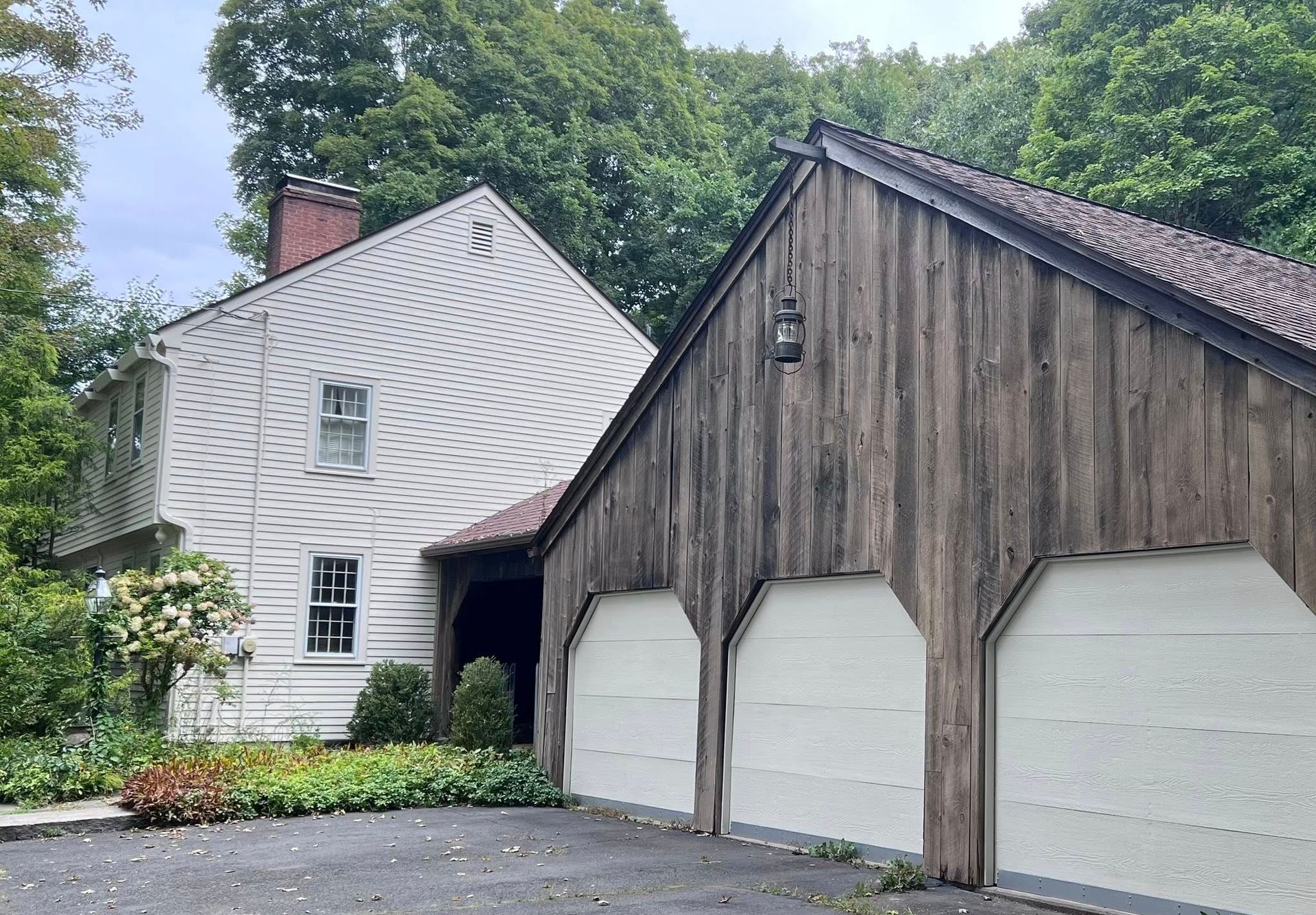 White house with three-car garage. The garage has white doors and is connected to the house via a portico.