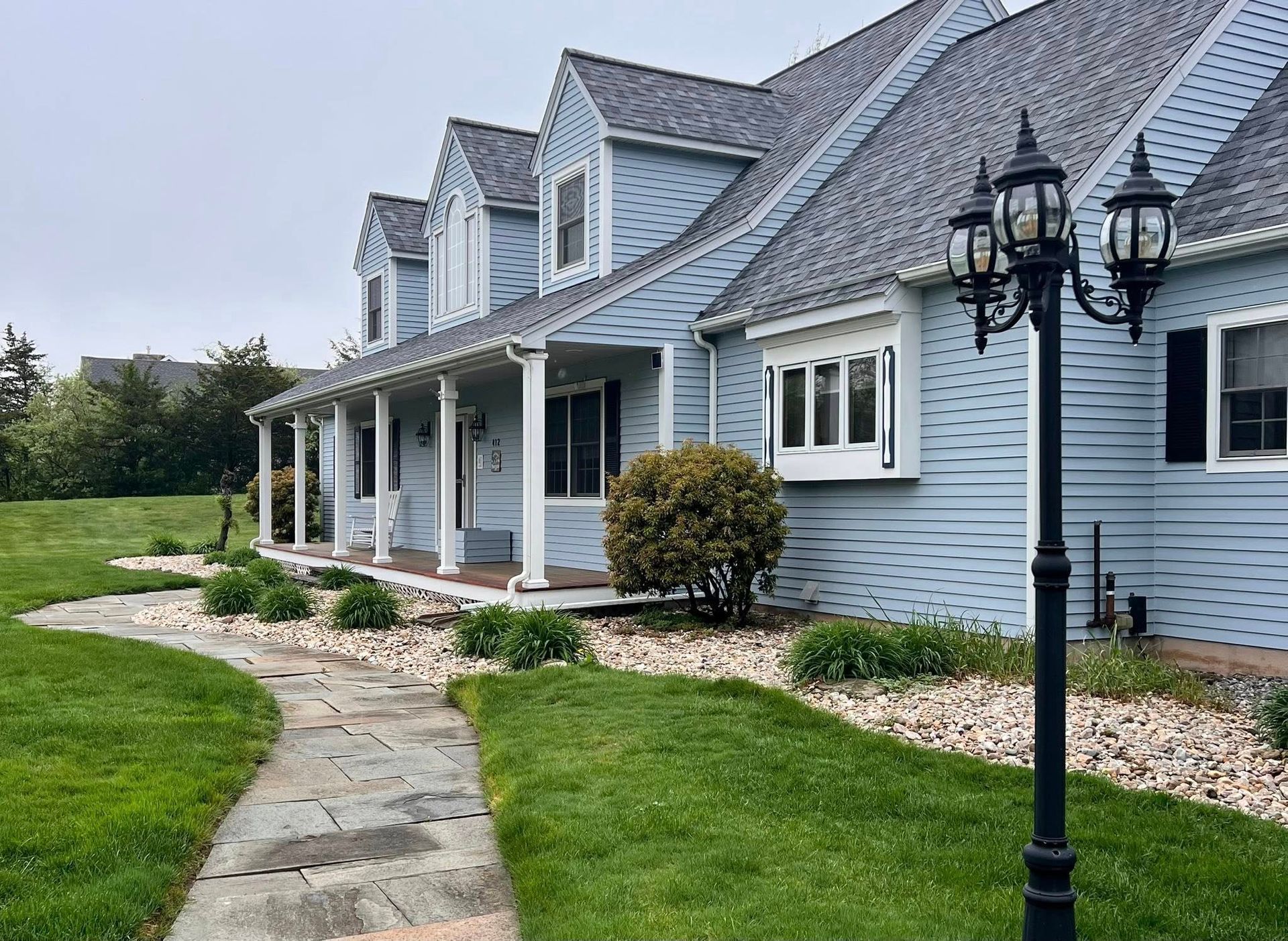 Blue house with stone path and lamppost on a cloudy day.