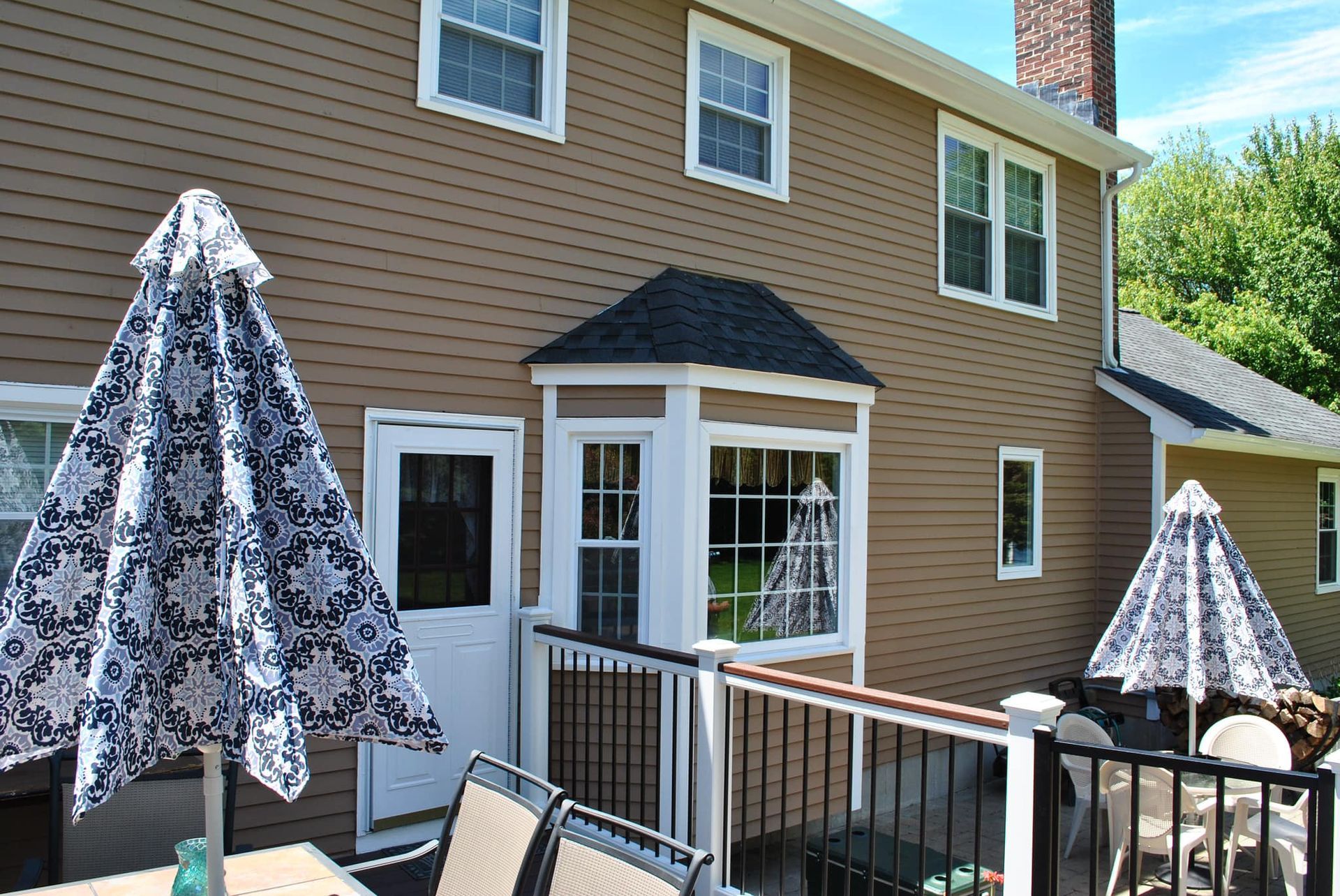 Brown house with a deck and umbrellas, sunny day.