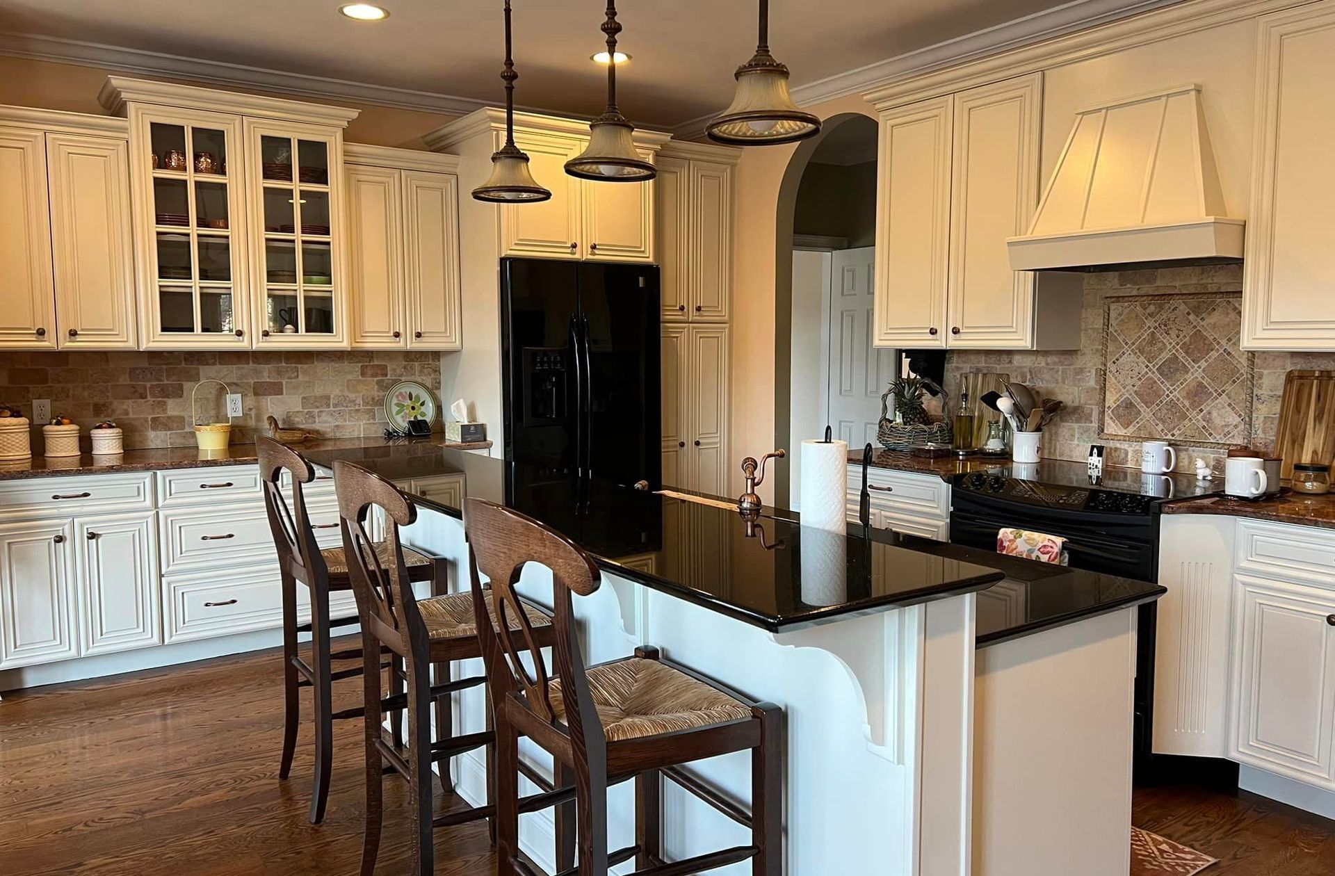A kitchen with white cabinets , black counter tops , and a large island.