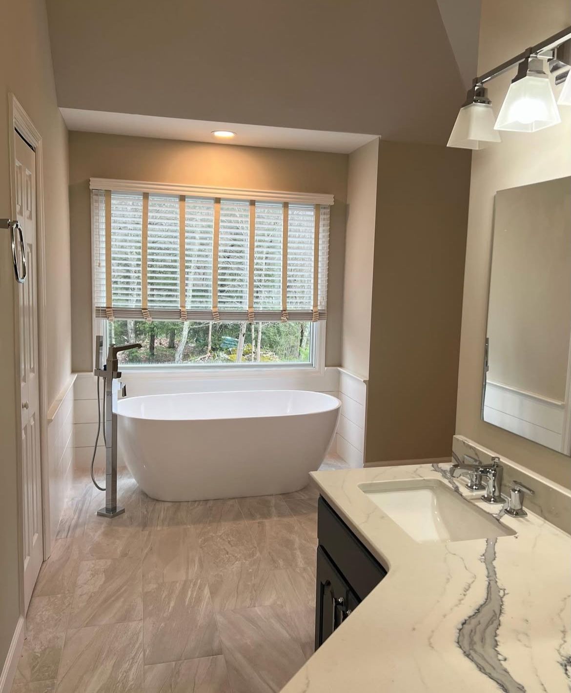 A bathroom with a tub, sink, mirror and window