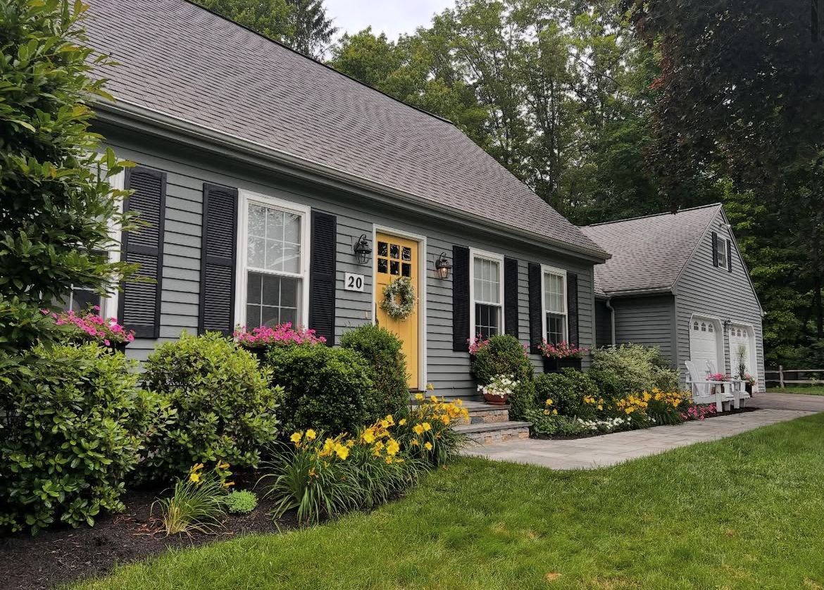 A gray house with a yellow door and black shutters