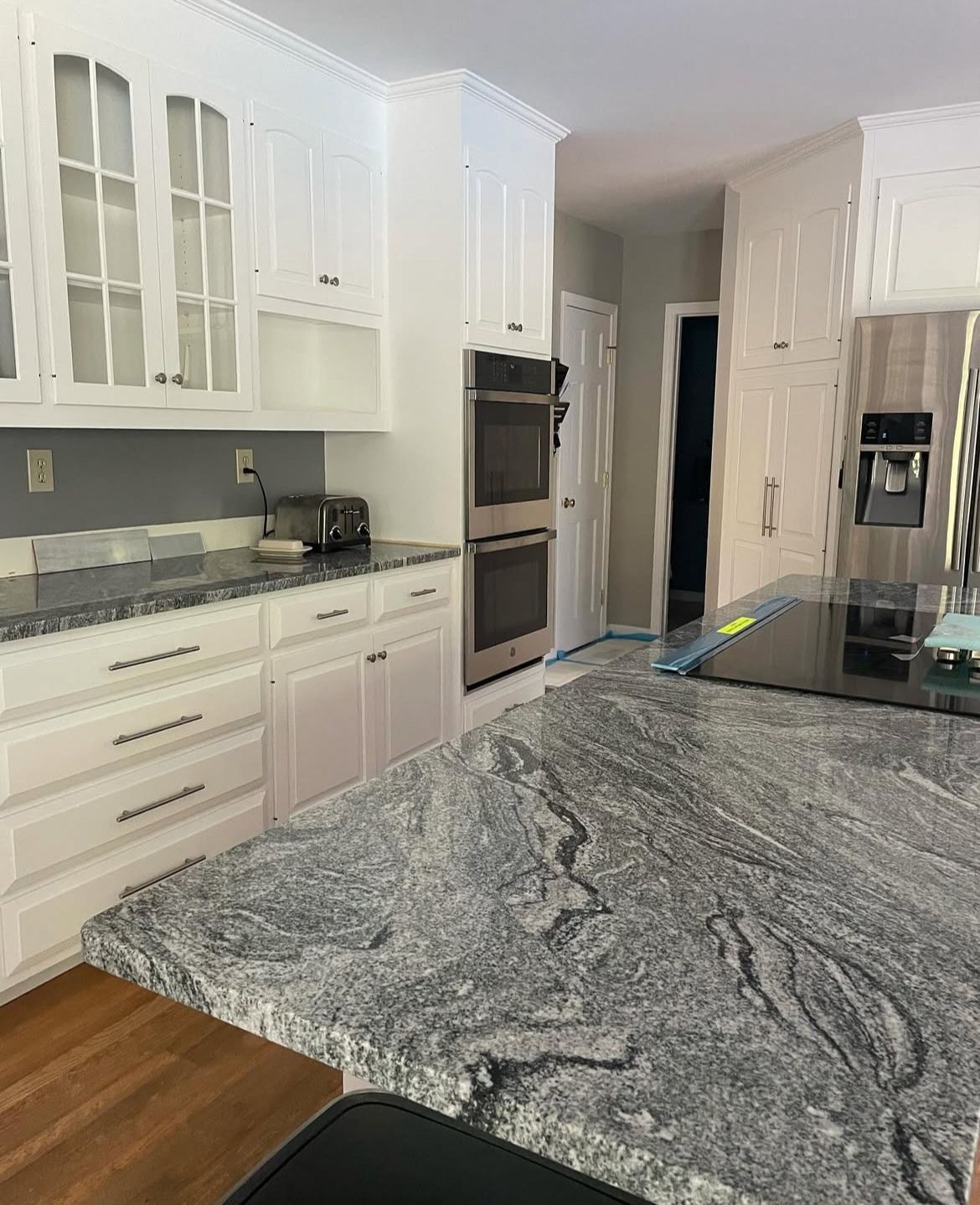 A kitchen with granite counter tops and white cabinets