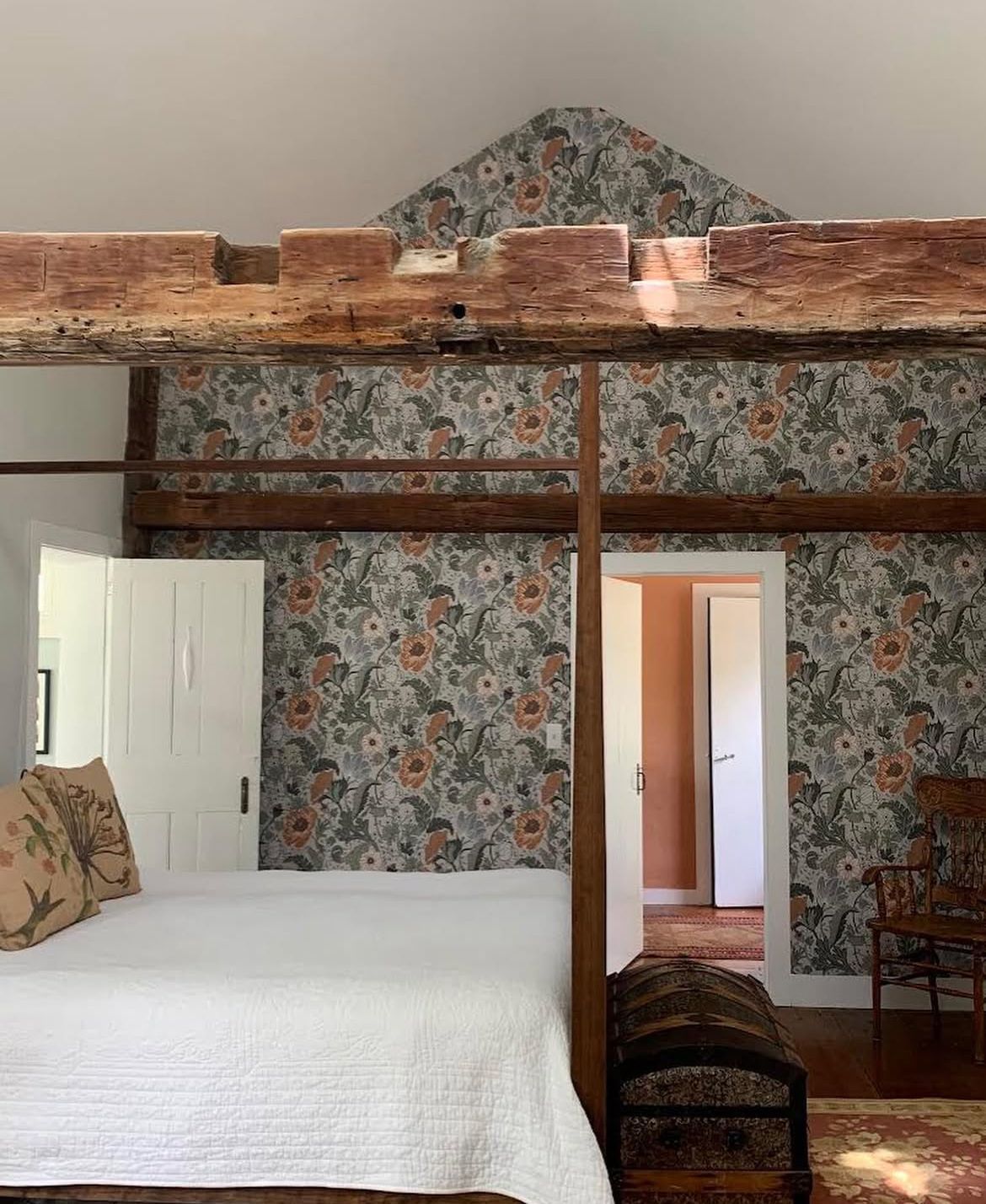 A bedroom with a four poster bed and floral wallpaper