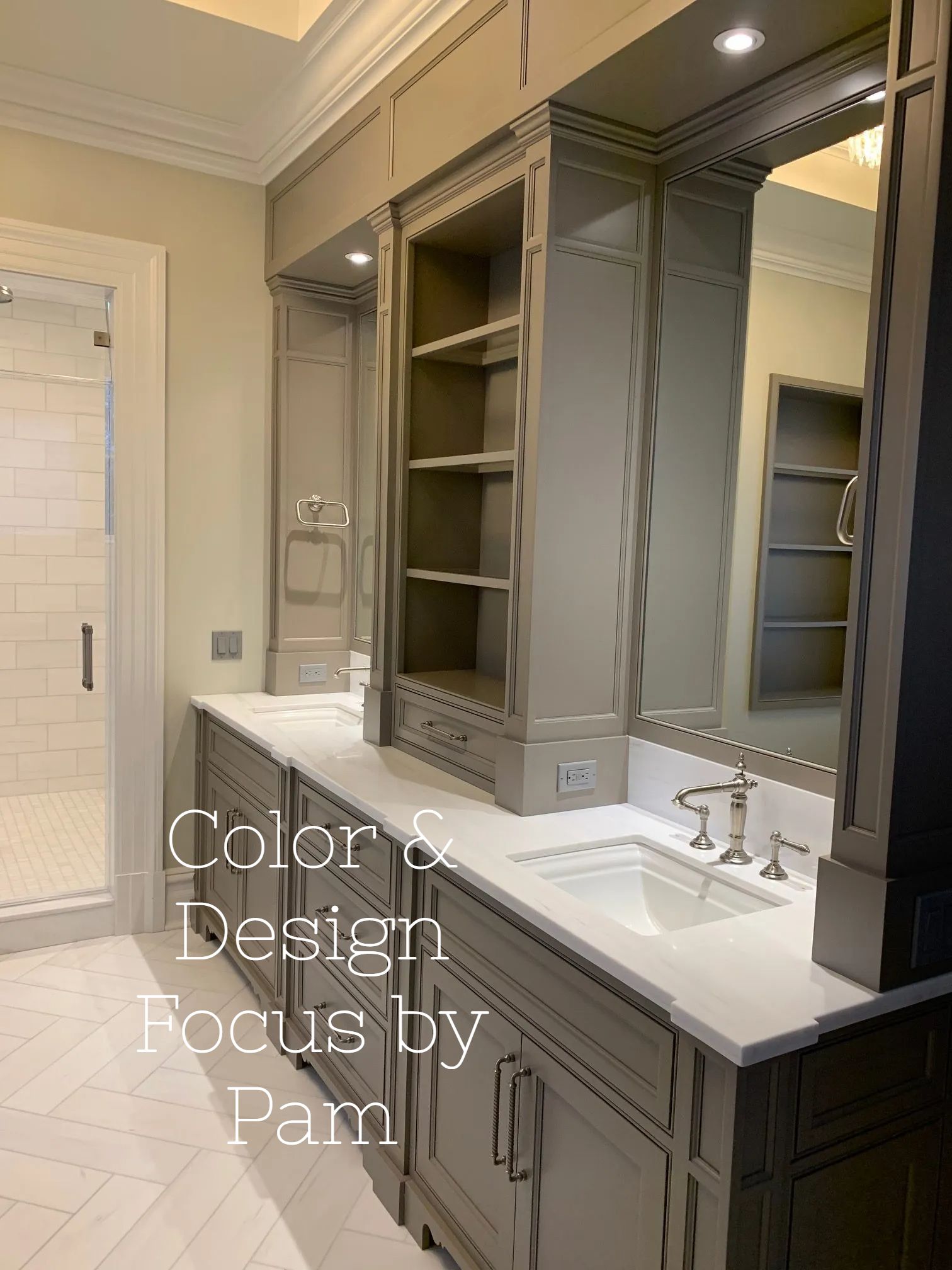Gray bathroom with white countertops, built-in storage, and a large mirror. A walk-in shower is visible in the background.