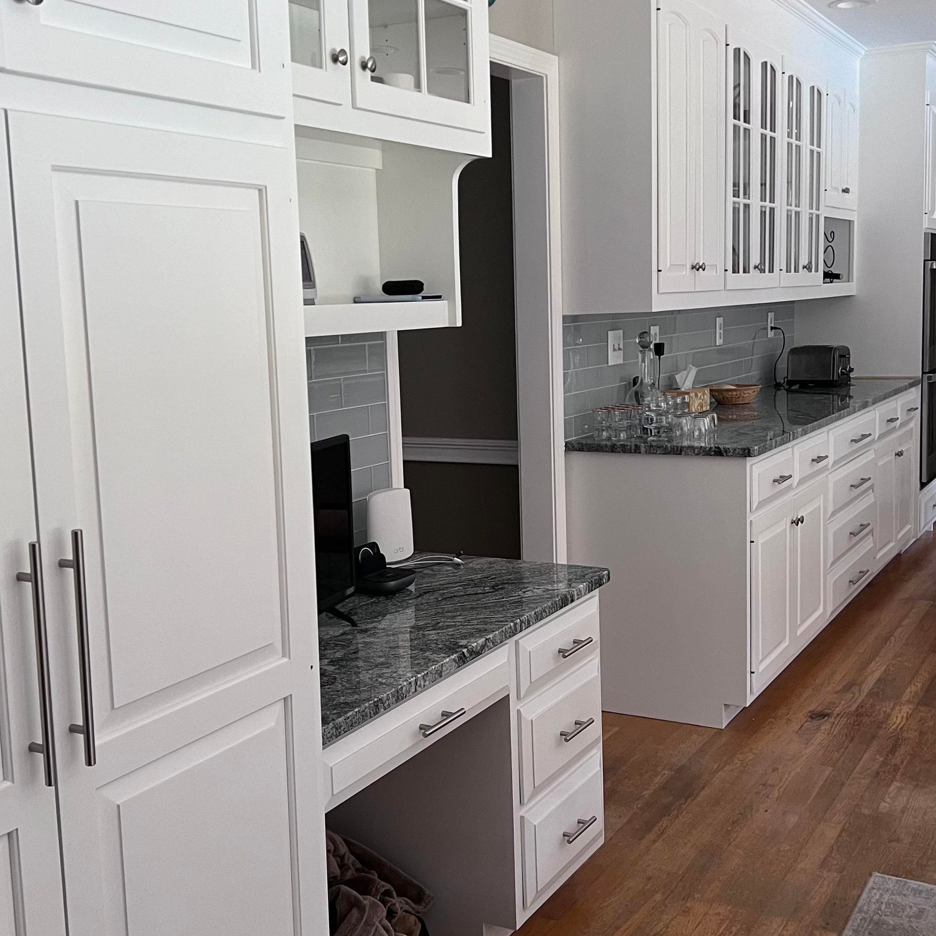 White kitchen with granite countertops, cabinets, and a built-in desk.