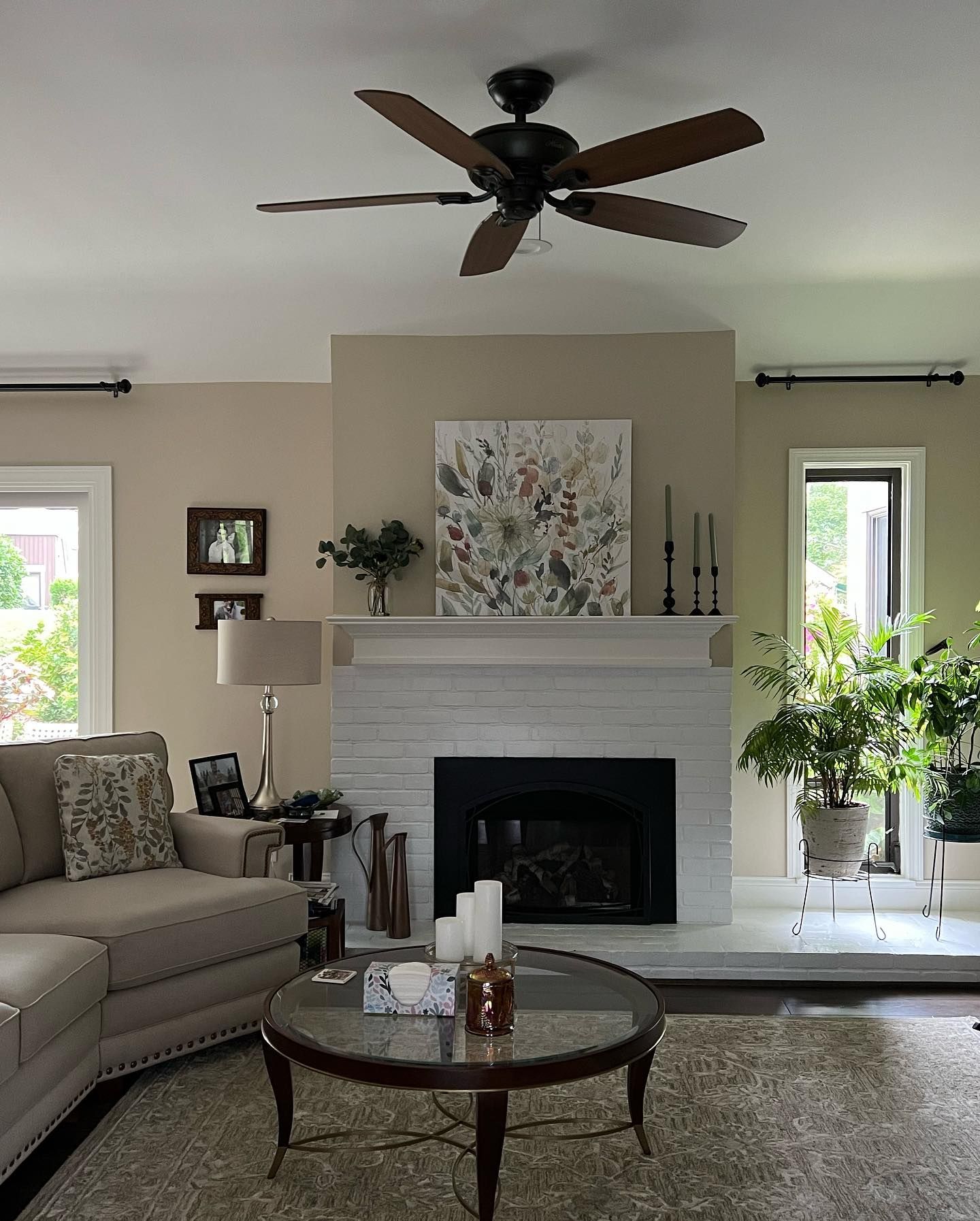 Living room with fireplace, sofa, and coffee table. Beige walls, neutral decor, and a ceiling fan.