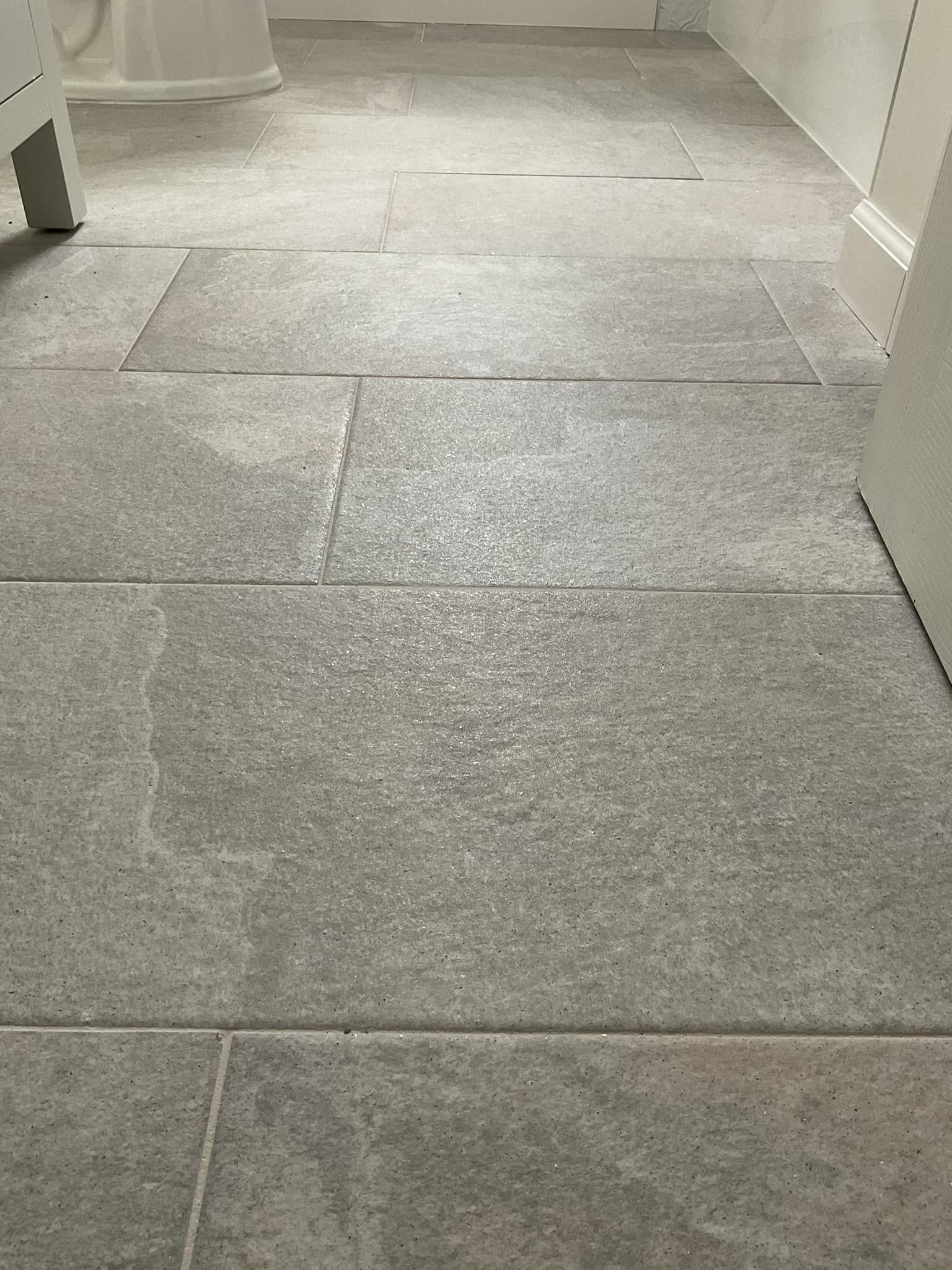 Gray stone tile flooring in a bathroom, viewed from a low angle.
