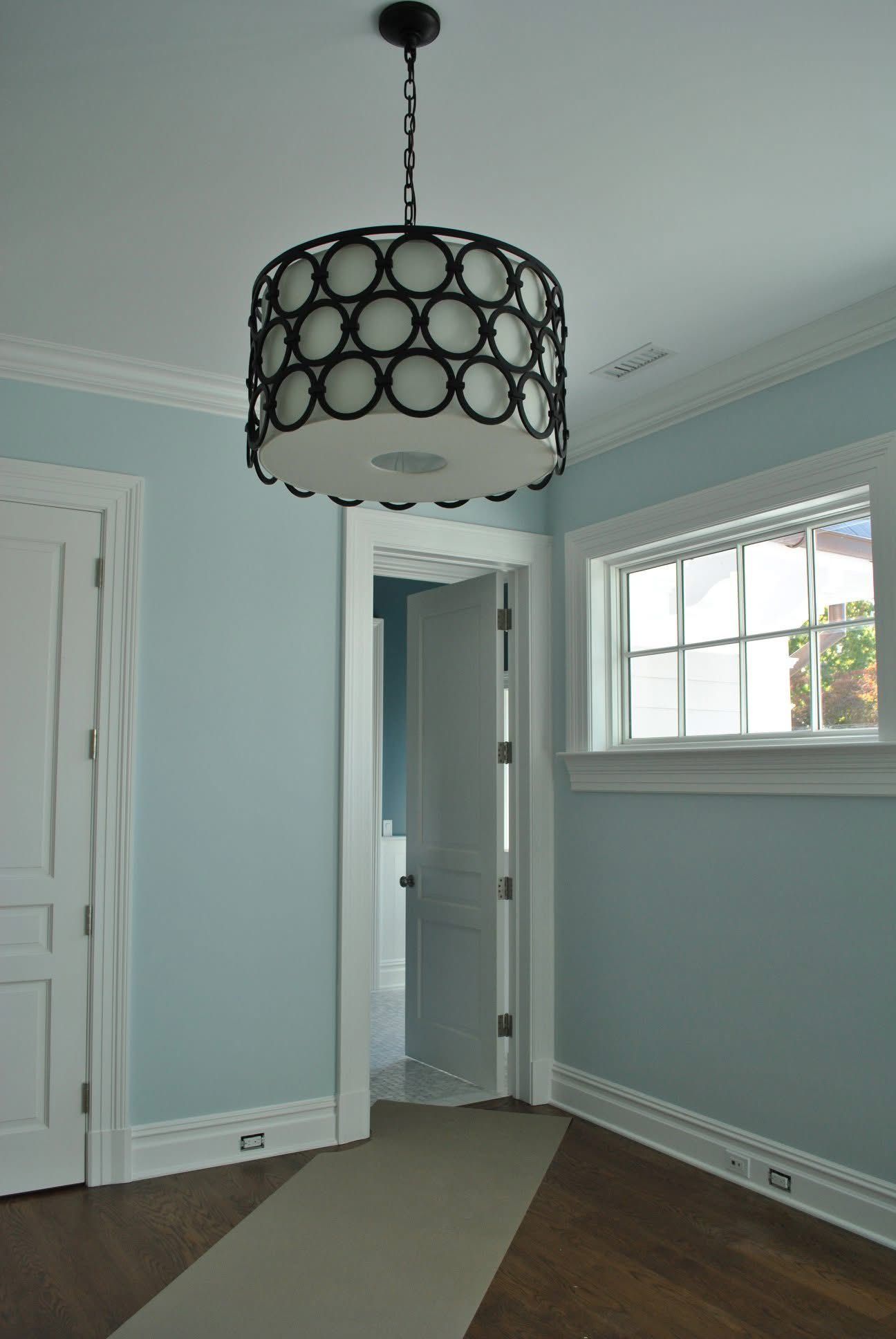 Bedroom with light blue walls, white trim, and a dark circular chandelier.