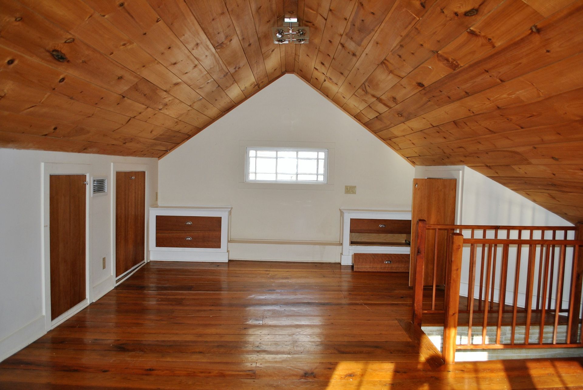 An empty attic with wooden floors and white walls
