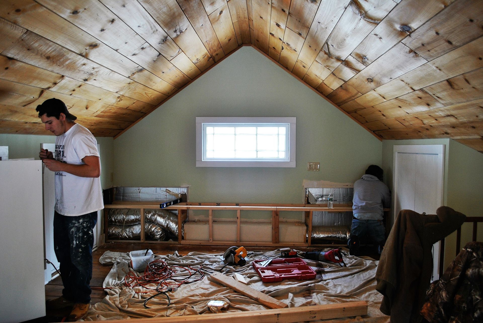 A man in a white shirt is working in an attic