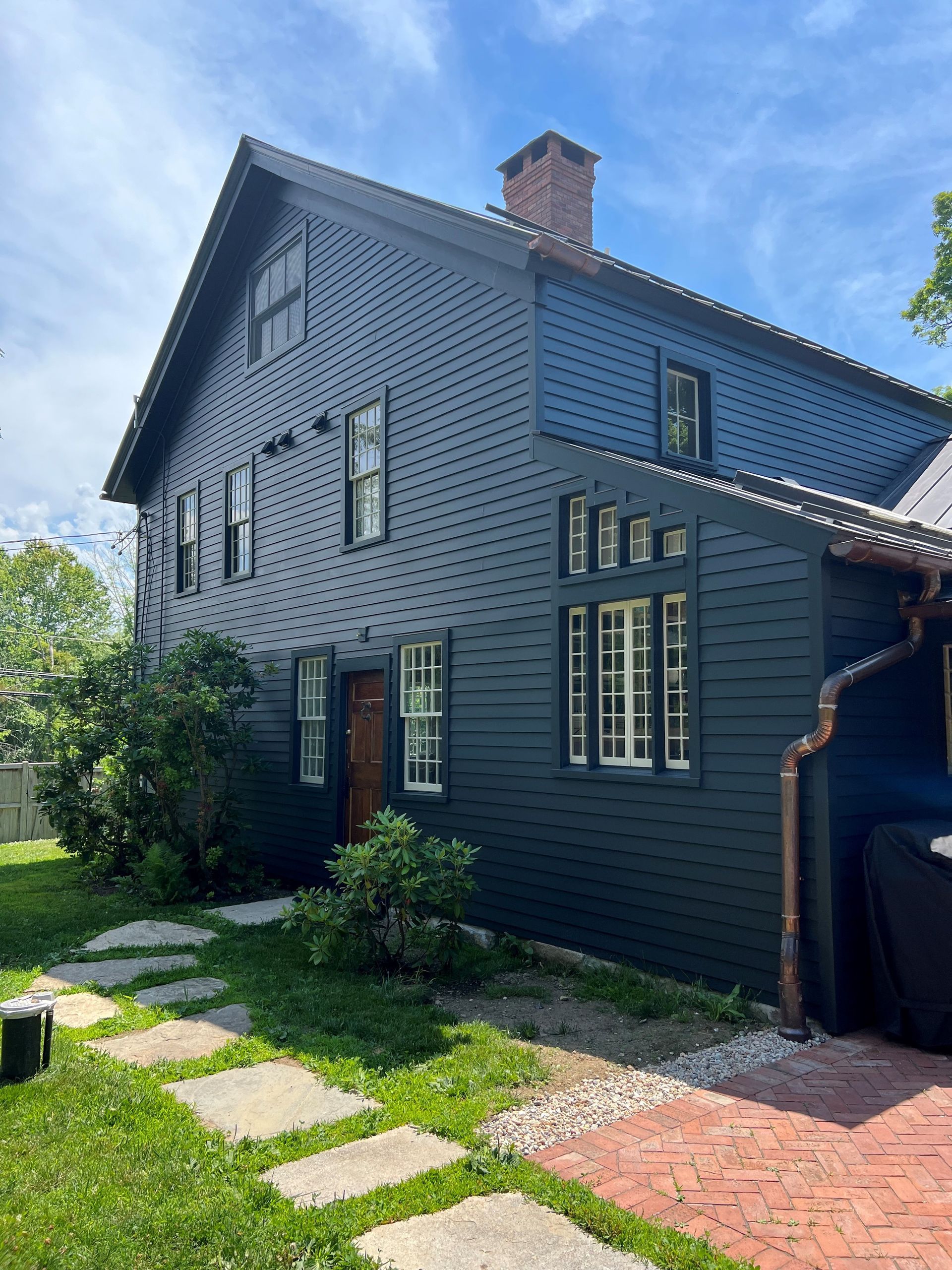 A large black house with a brick walkway leading to it.