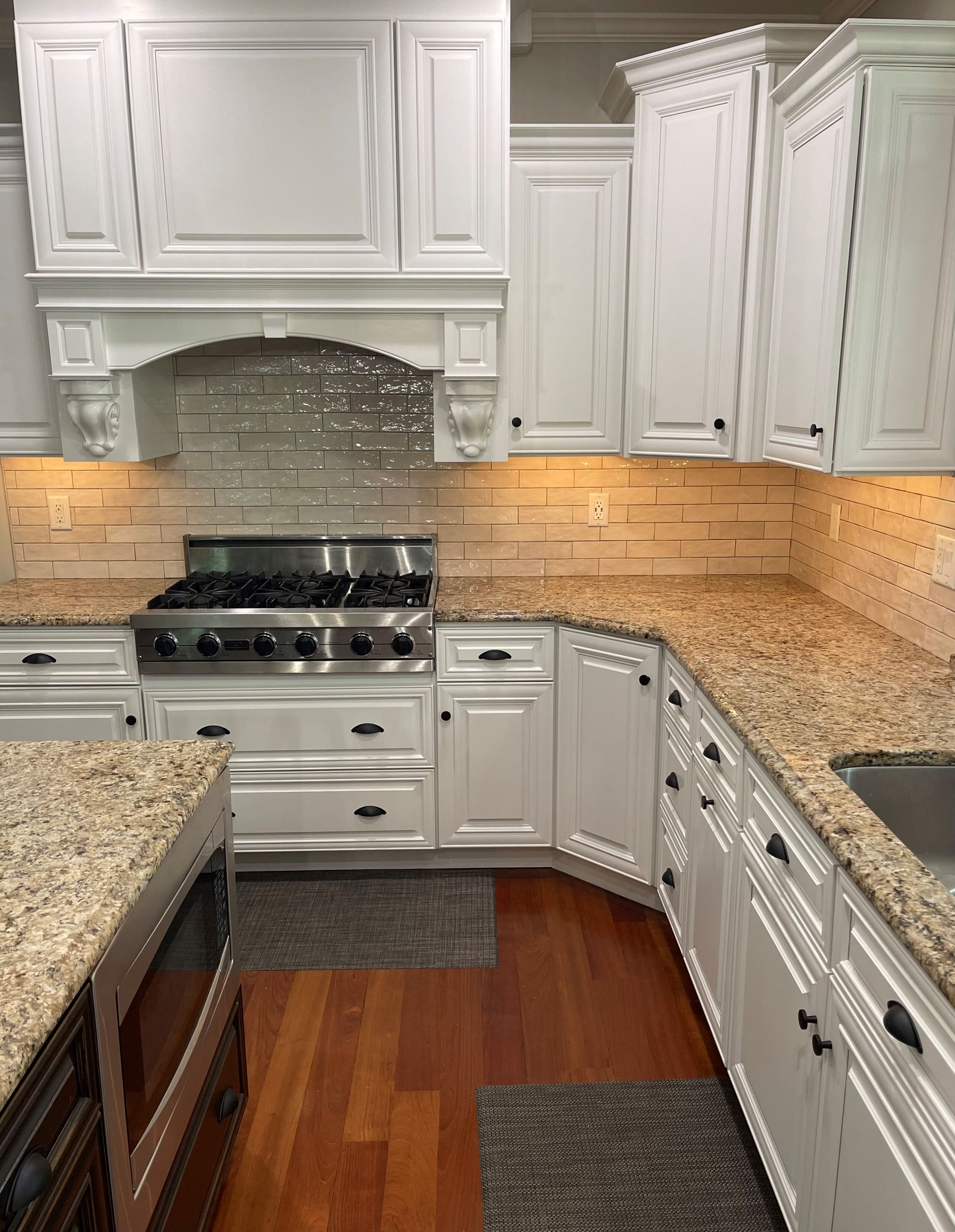 A kitchen with white cabinets , granite counter tops , and a stove.