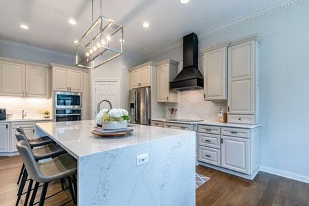 A kitchen with white cabinets , granite counter tops , stainless steel appliances and a large island.