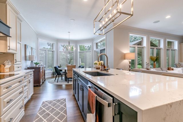 A kitchen with marble counter tops , wooden cabinets , stainless steel appliances and a large island.