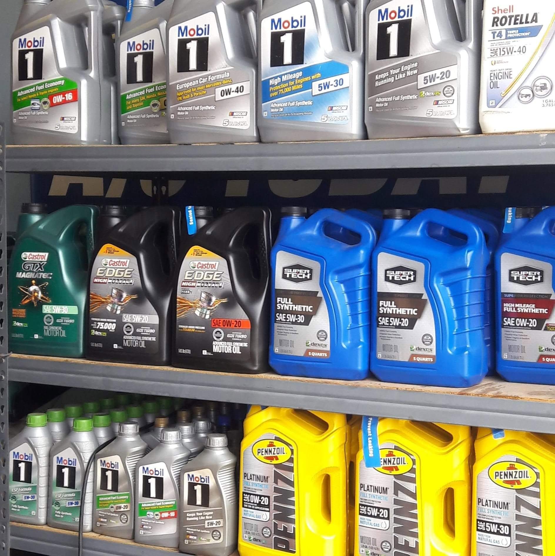 Shelf of motor oil bottles in a store, with Mobil 1 and Pennzoil containers on display.