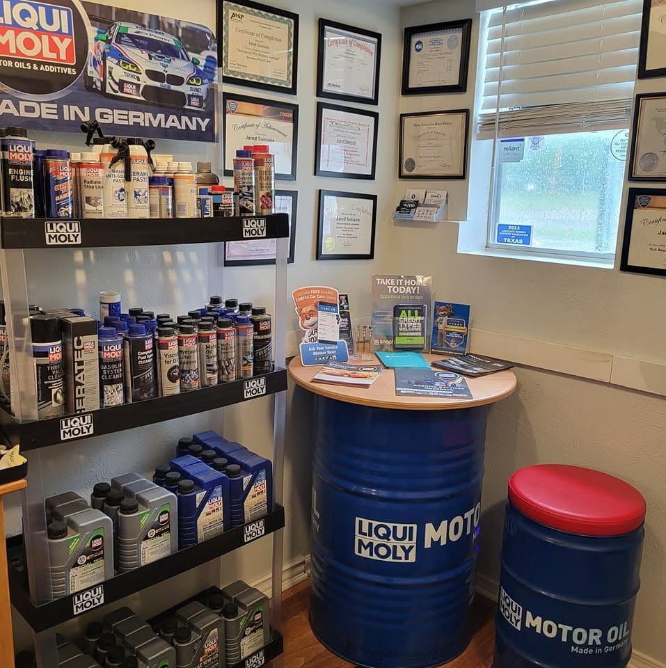 Liqui Moly product display in an office, with shelves, certificates, brochures, and branded barrel seating.