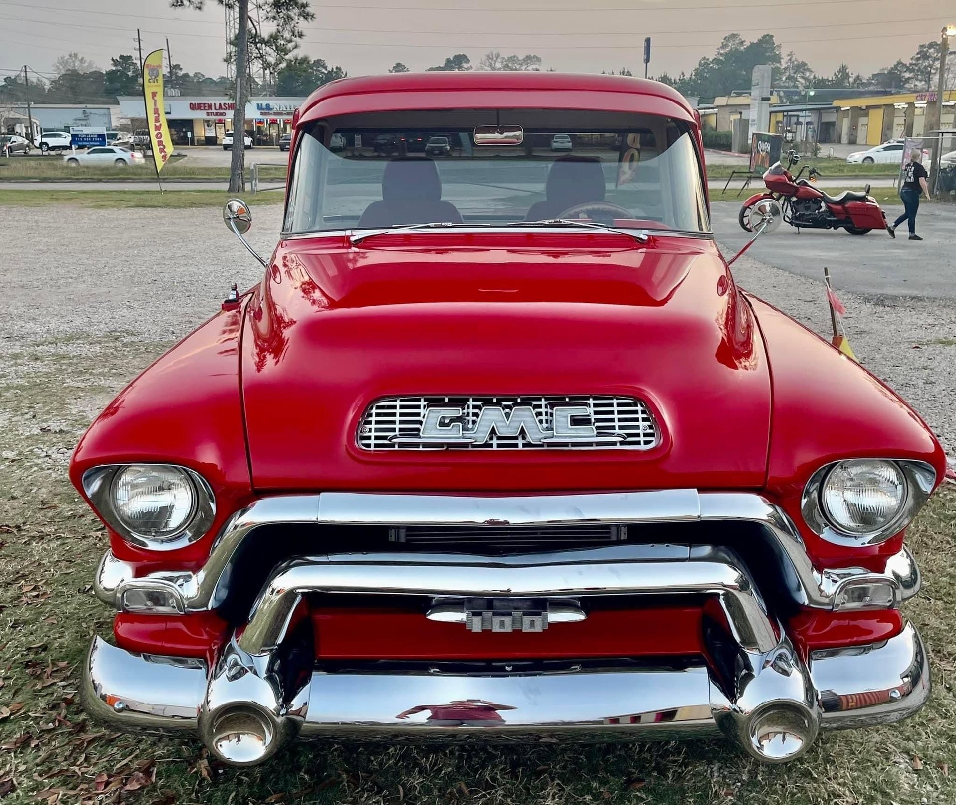 Red vintage pickup truck parked outdoors, front view, with chrome bumper and grille