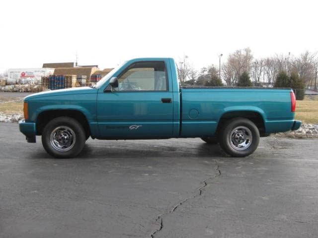 Teal pickup truck parked on a road with snow along the roadside