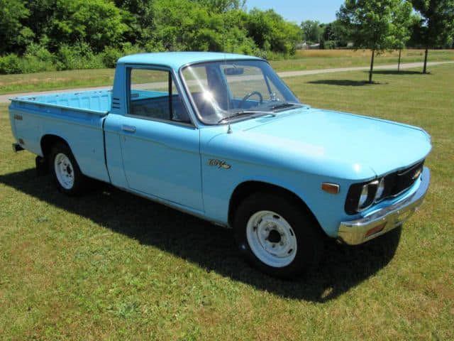 Light blue vintage pickup truck parked on grass in a sunny field