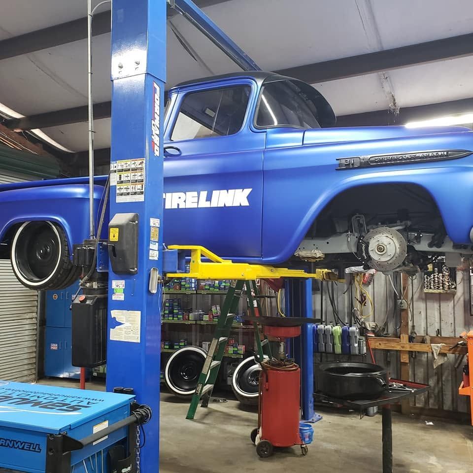 Blue classic car on a lift in an auto repair shop garage