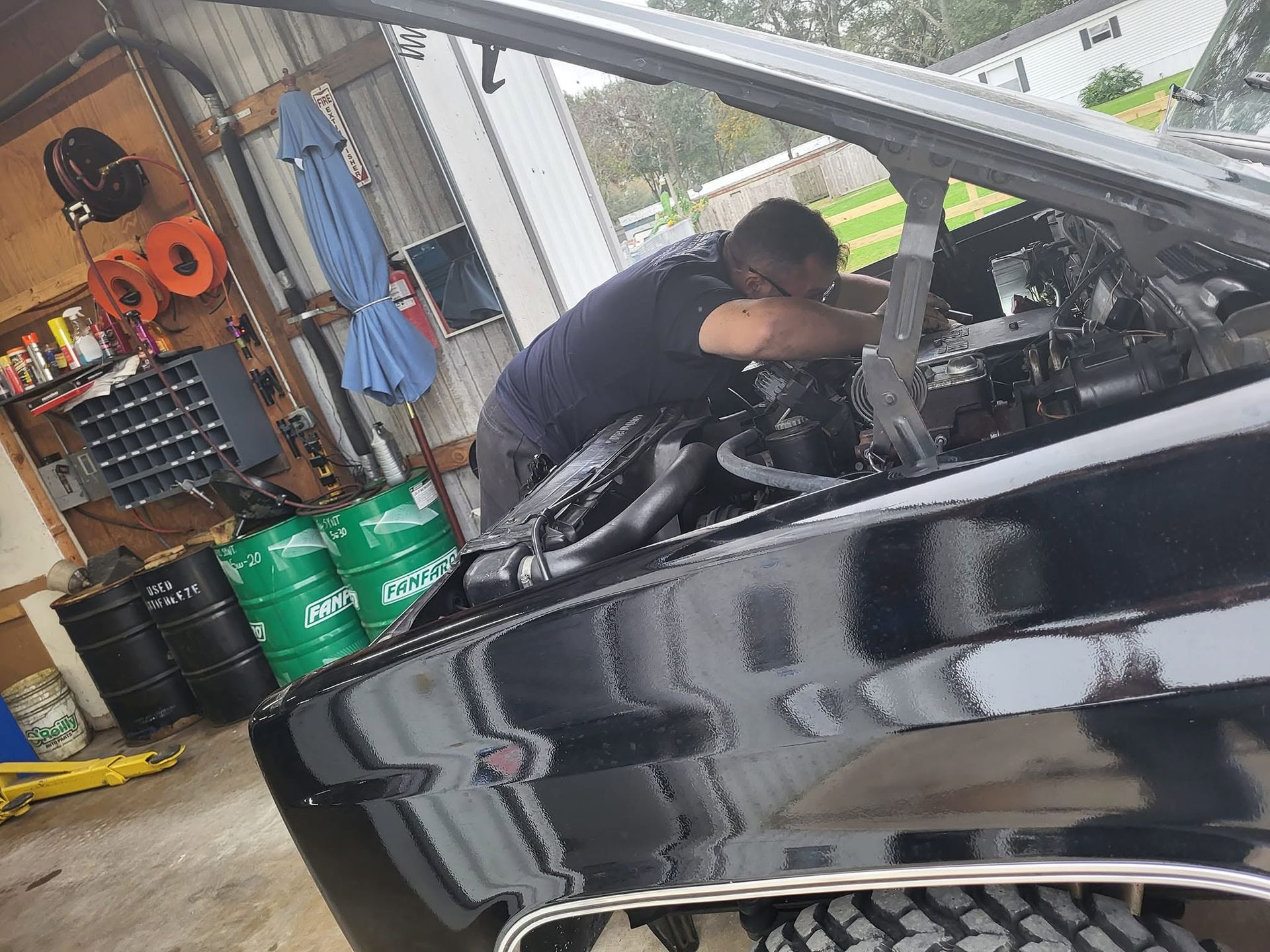 Mechanic working under the hood of a black car in a garage