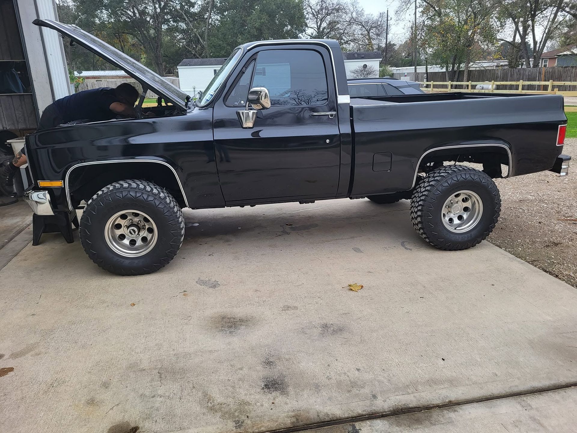 Black pickup truck with hood open, parked in a driveway.